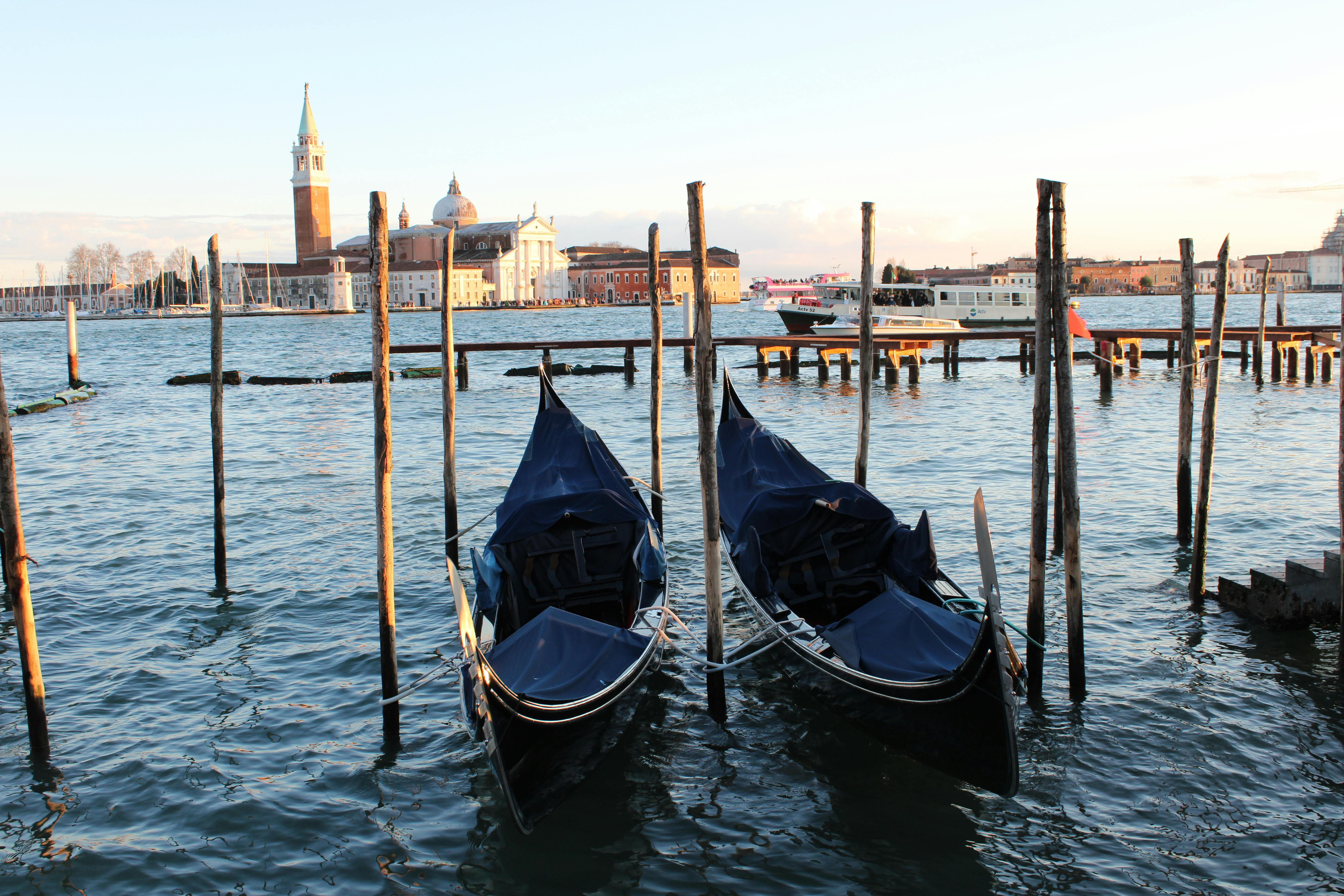 Venetian gondolas moored against a beautiful sunset view of historical buildings in Venice, Italy.