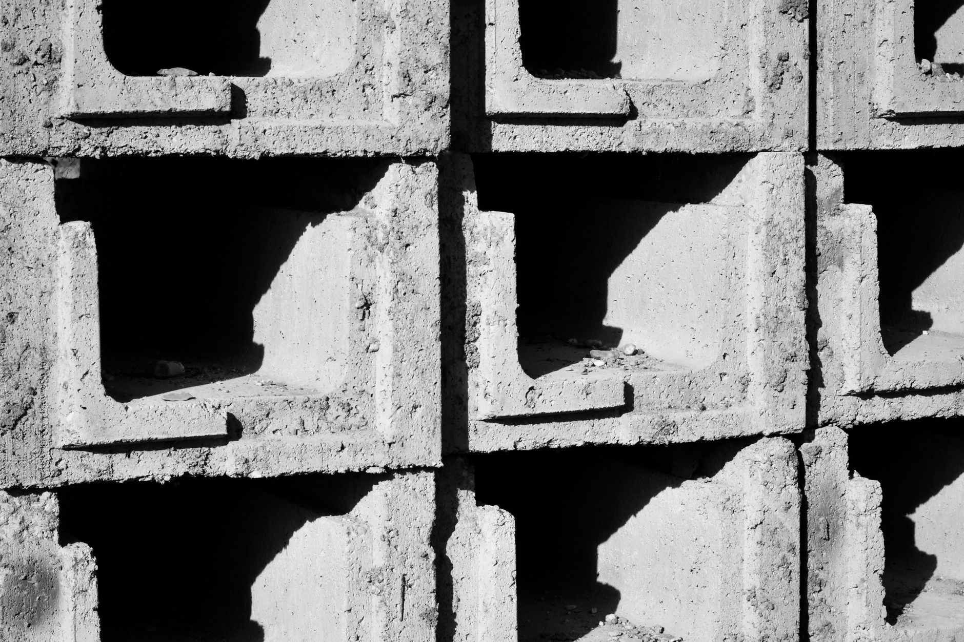 Detailed view of textured concrete blocks casting shadows in bright sunlight.