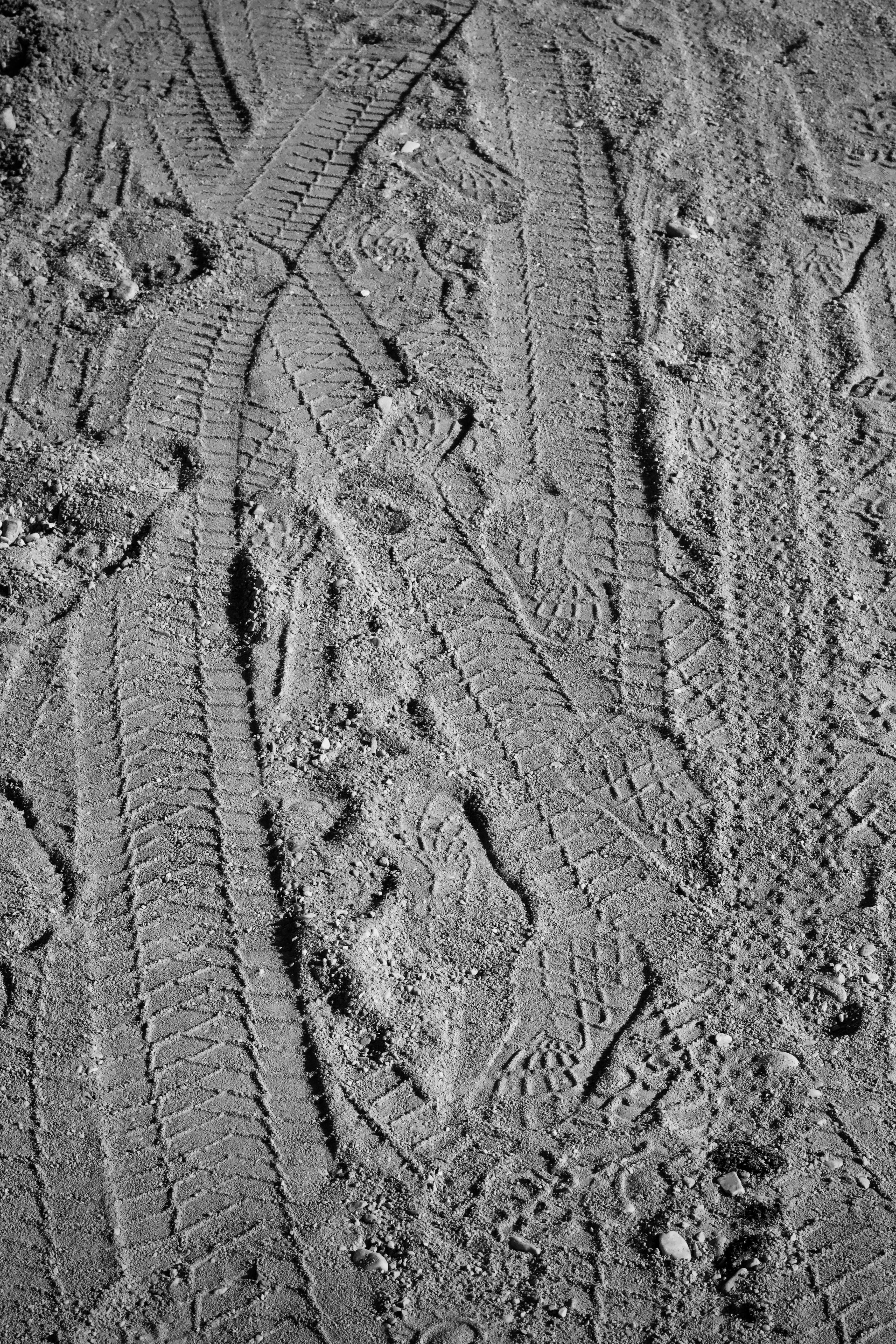 無料 砂地に残ったタイヤと靴の跡の詳細なクローズアップ。 写真素材