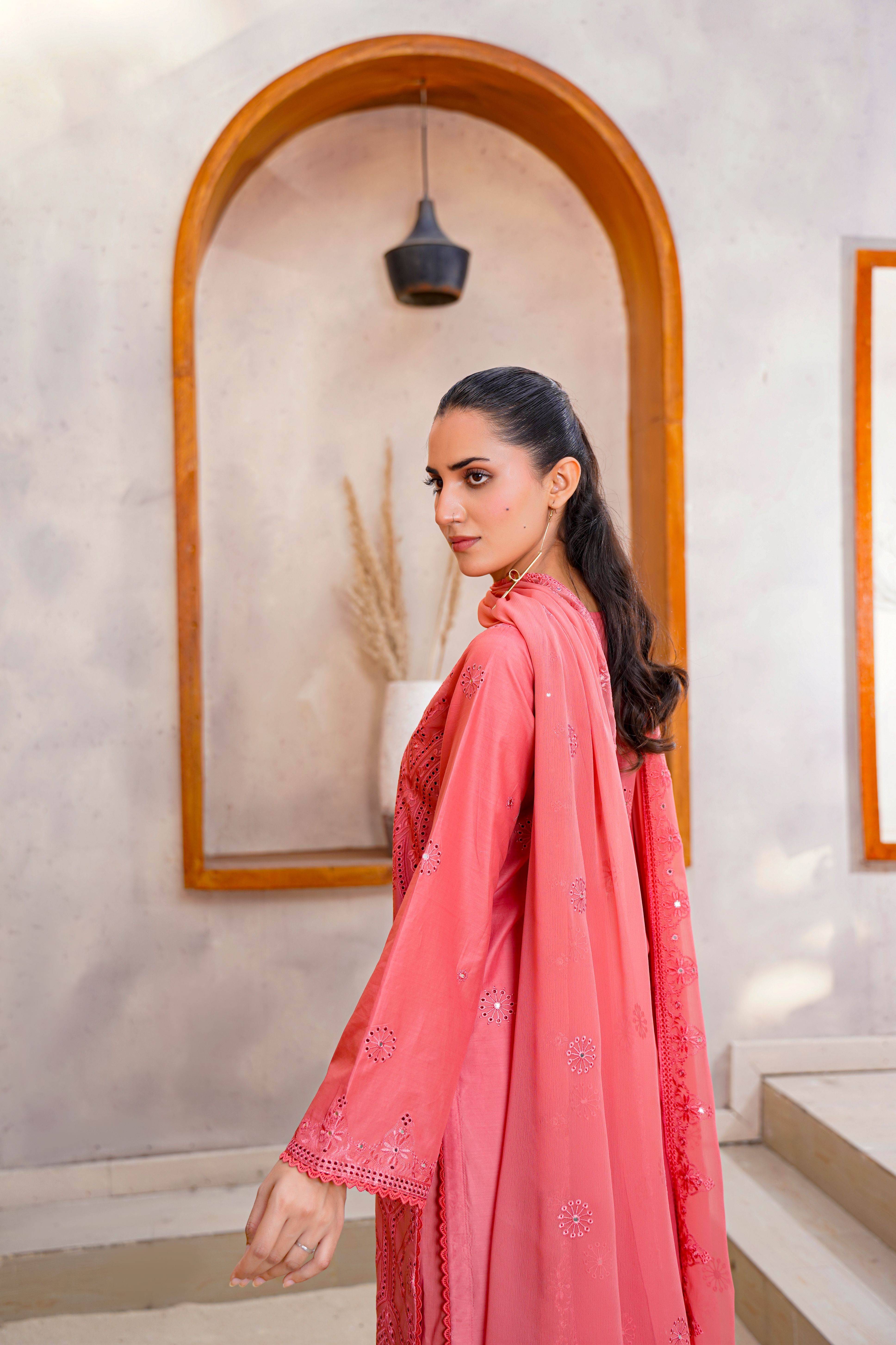 Model in embroidered pink dress poses elegantly in a New York setting.