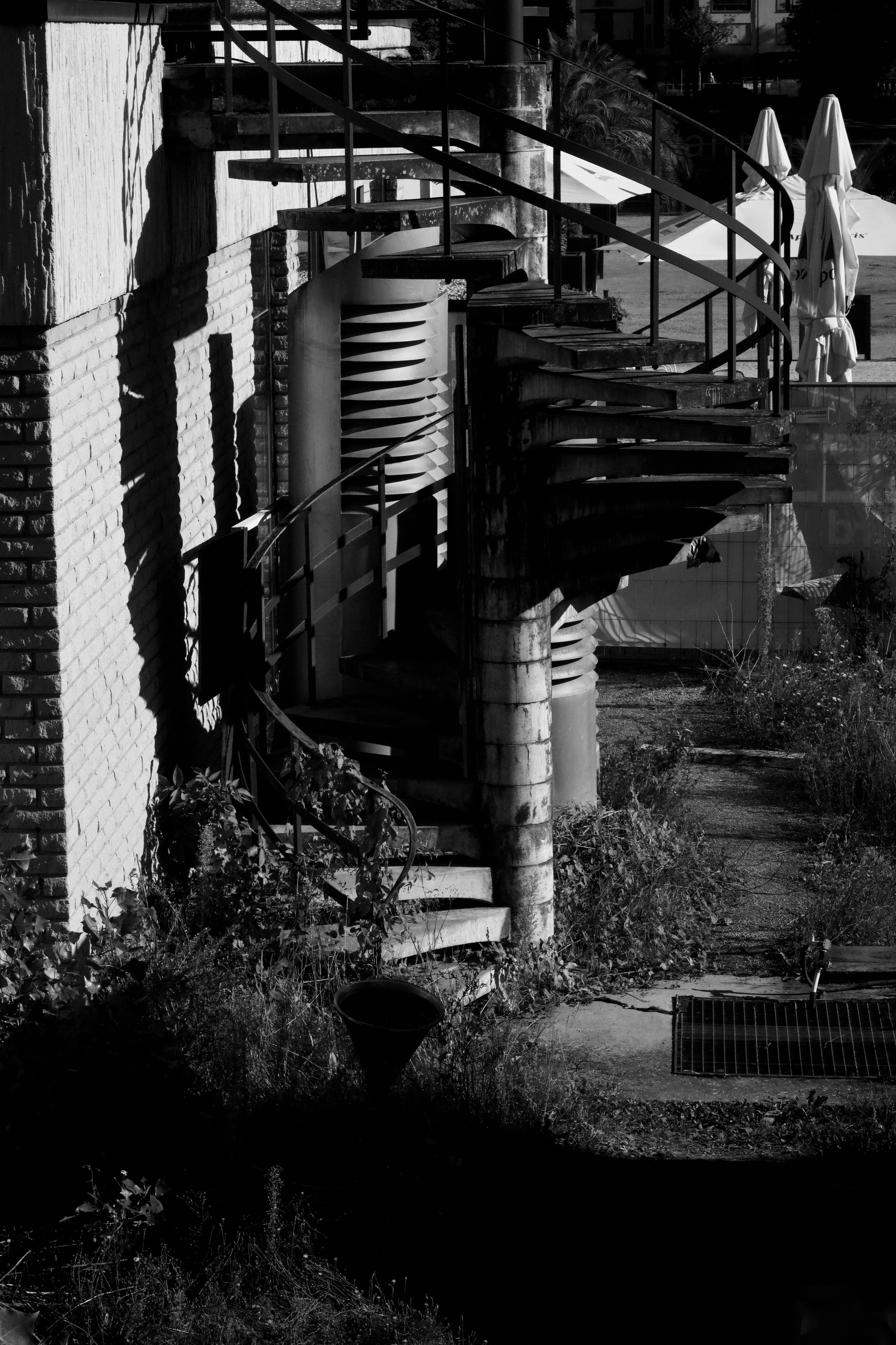 Free A shadowy spiral staircase against a textured wall in black and white. Stock Photo