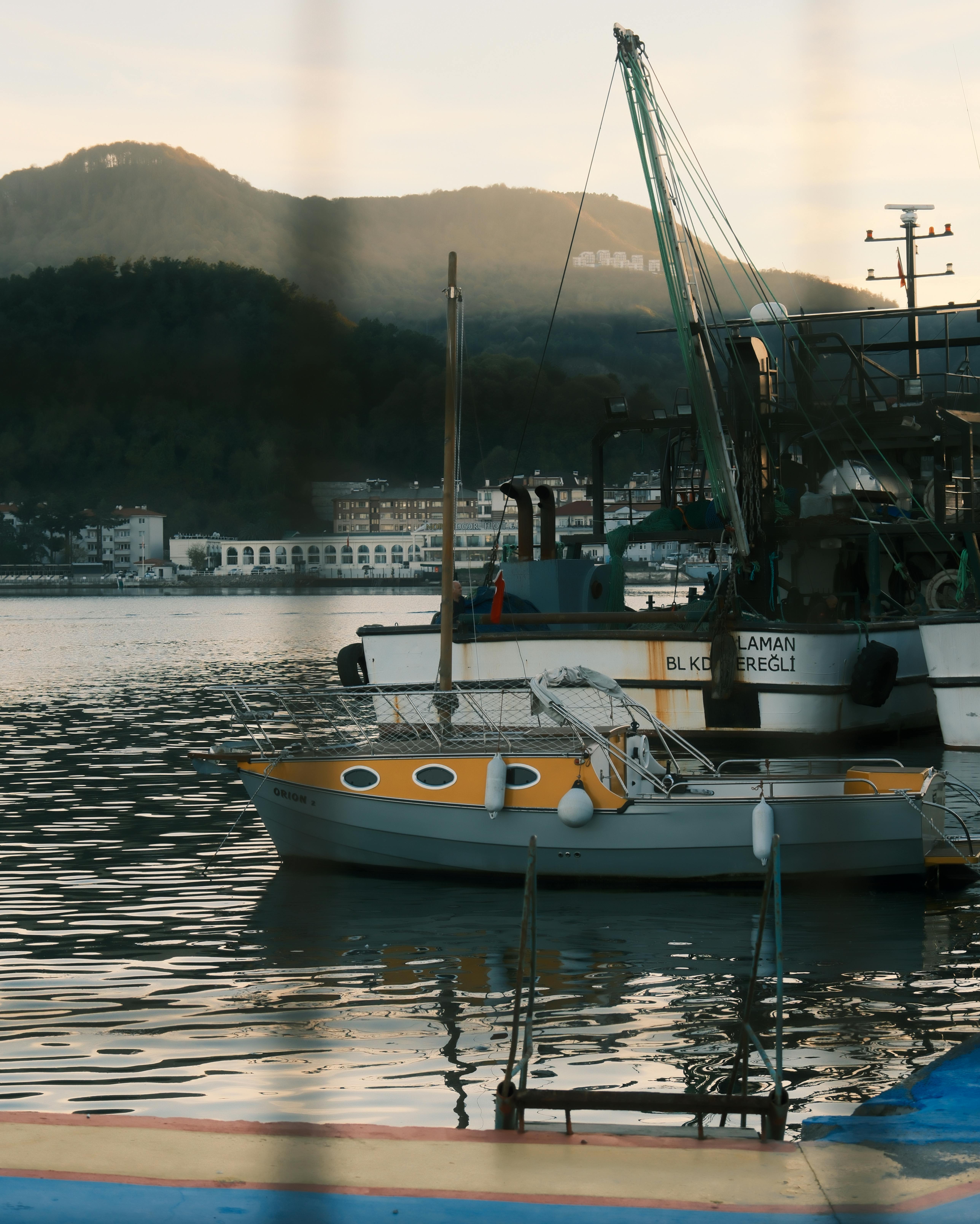 бесплатная Лодки пришвартованы в гавани Амасра, Турция, на фоне заката и холмов. Стоковое фото