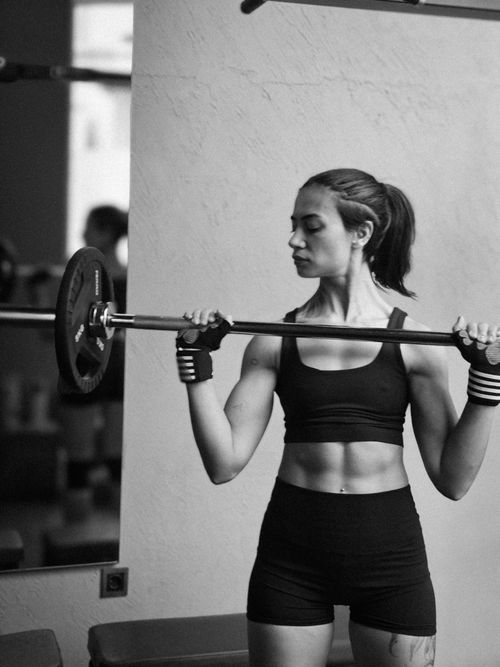 Free Athletic woman exercising with a barbell for strength training in a gym. Stock Photo