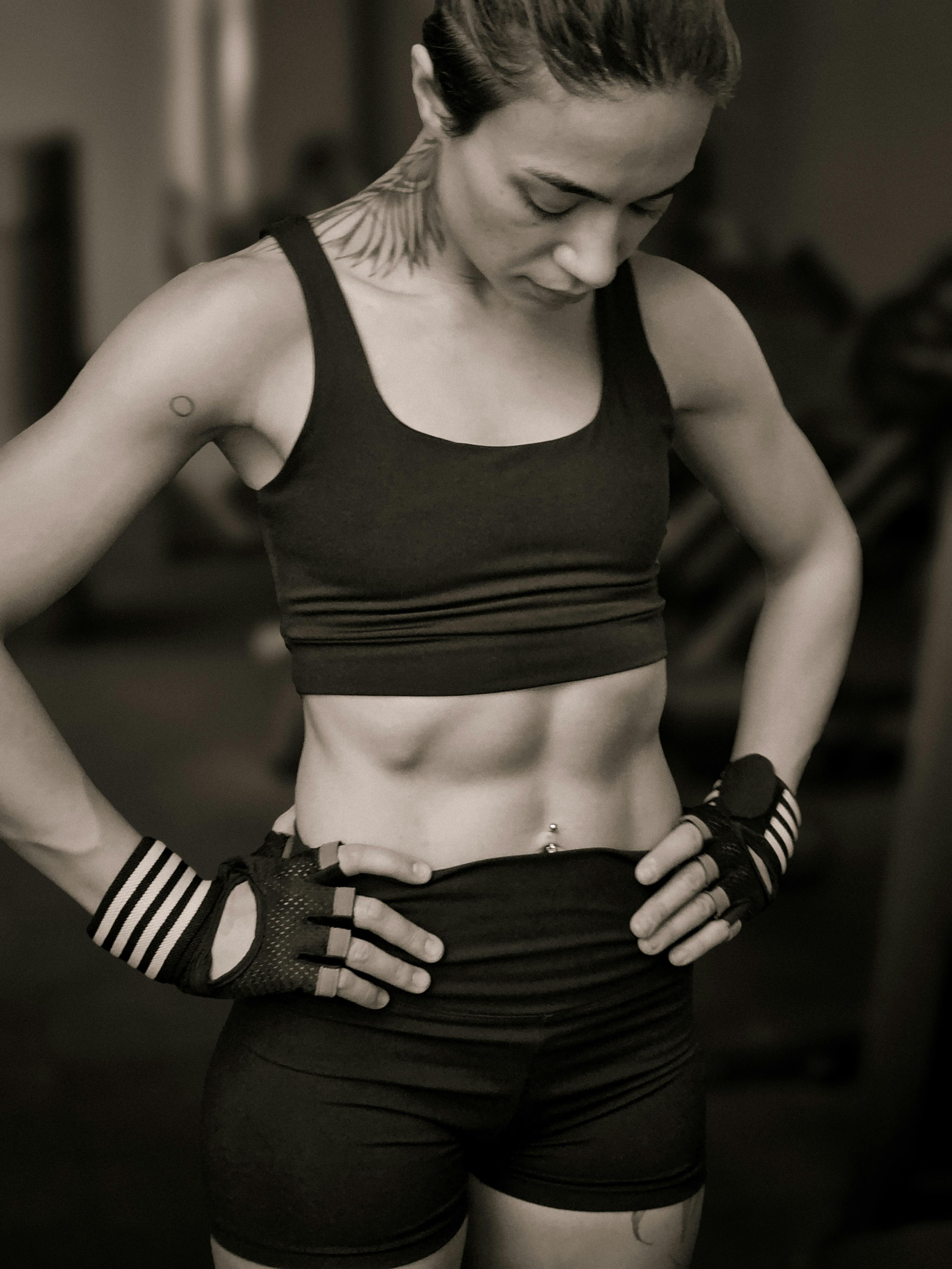 Free Focused female athlete wearing workout gear and gloves in a gym environment, showcasing fitness and strength. Stock Photo