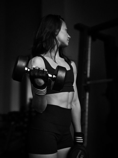 Free Female athlete lifting weights in a gym, showing strength and focus. Stock Photo