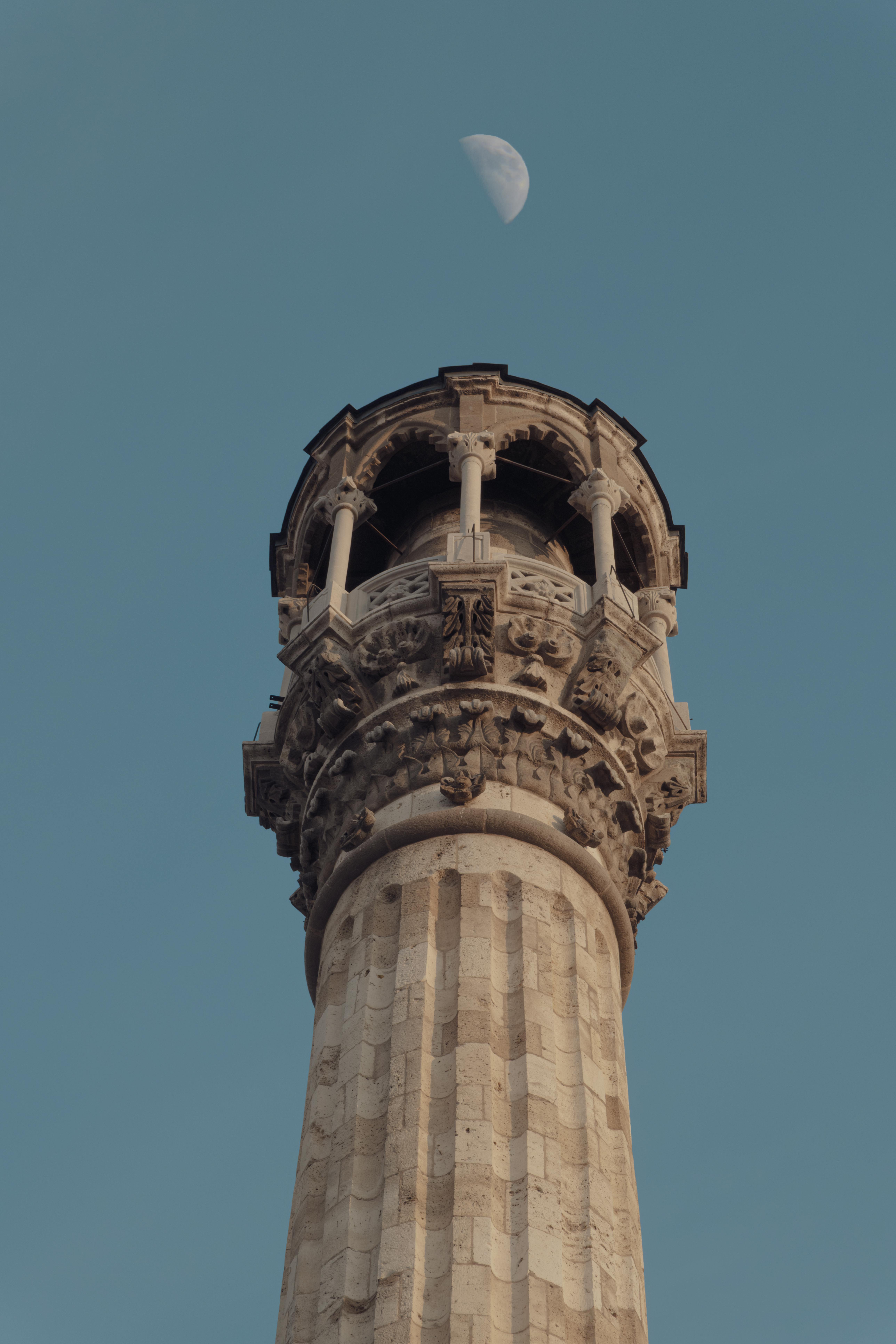 Free Historic Roman column with intricate carvings against a blue sky and half moon. Stock Photo