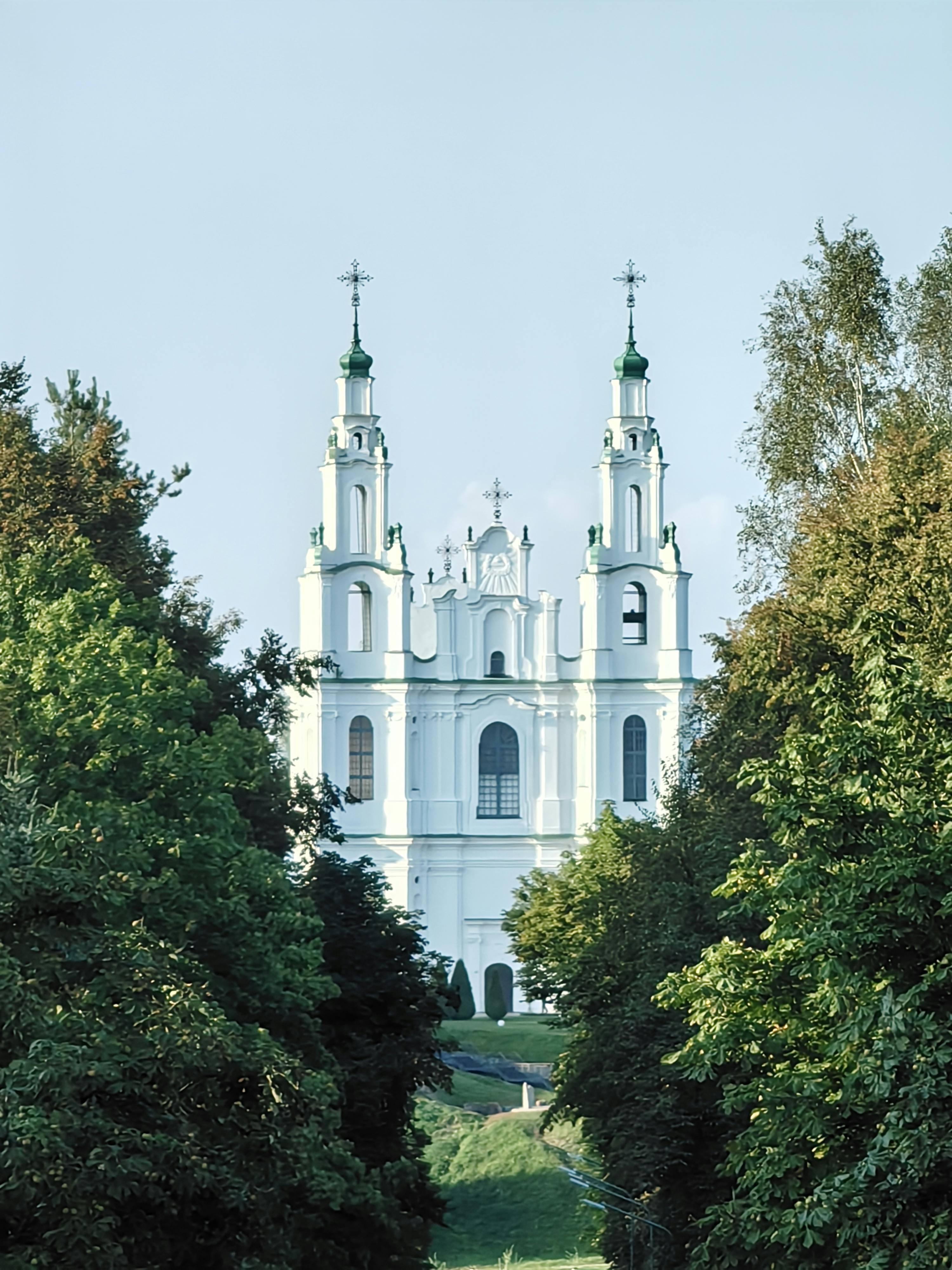無料 澄み切った青空の下、豊かな緑に囲まれた見事なバロック様式の教会。静寂と建築の美しさをとらえています。 写真素材