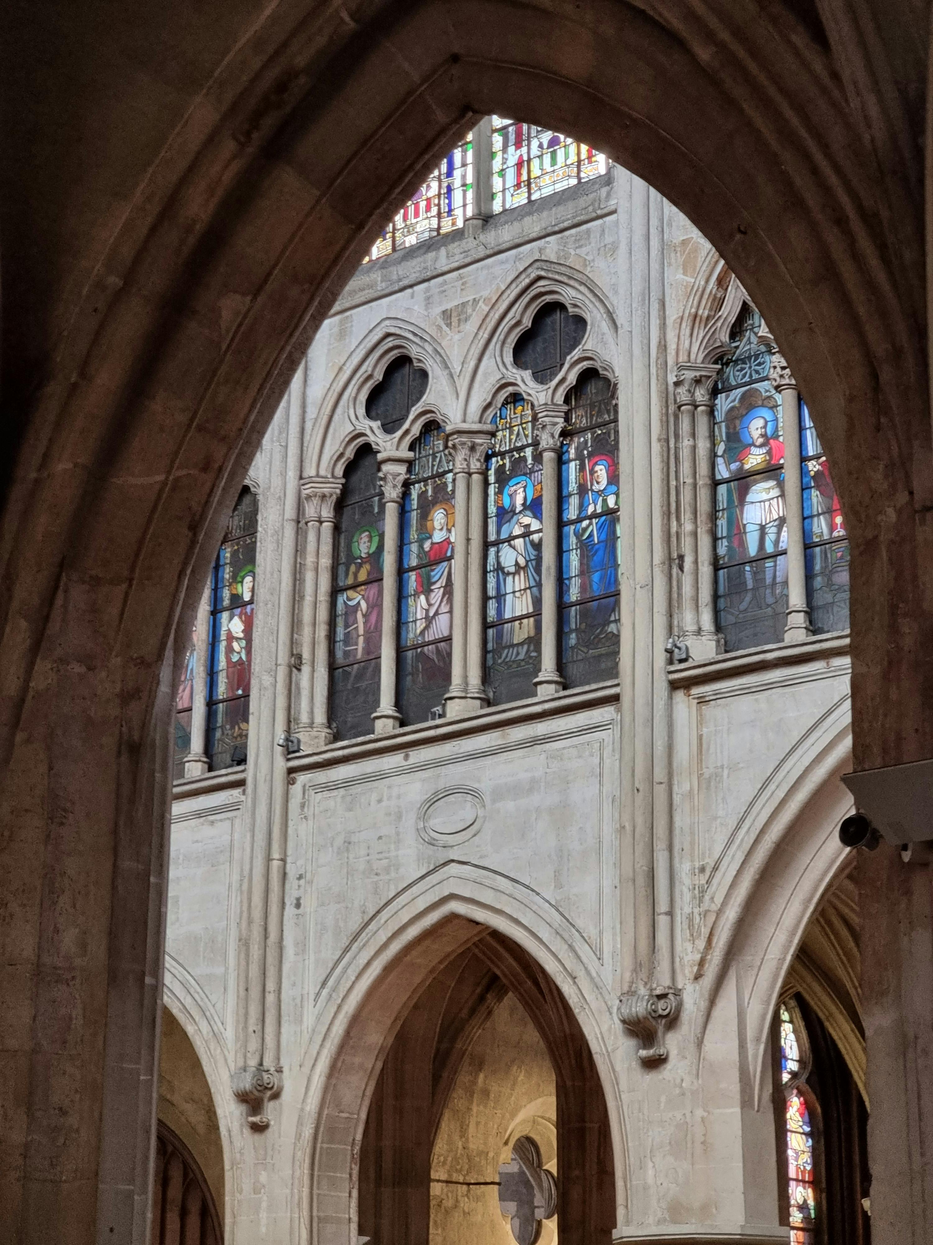 Gratis Imponerende glassmalerier i en parisisk gotisk kirke fanger opp livlige farger og religiøs kunst. Arkivbilde