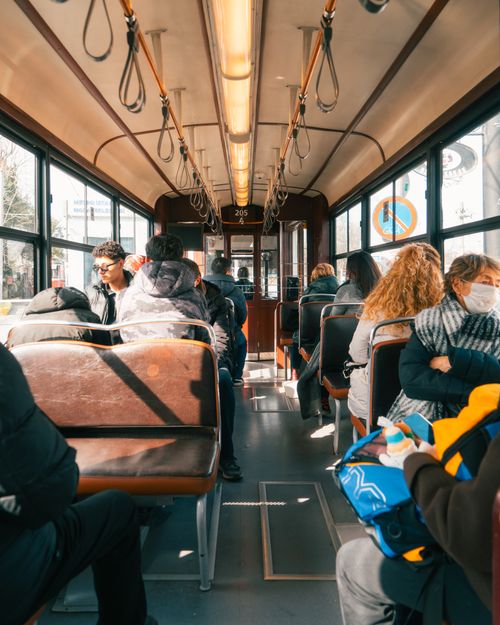 Free Passengers travel in a vintage tramway through a city, enjoying a sunny day. Stock Photo