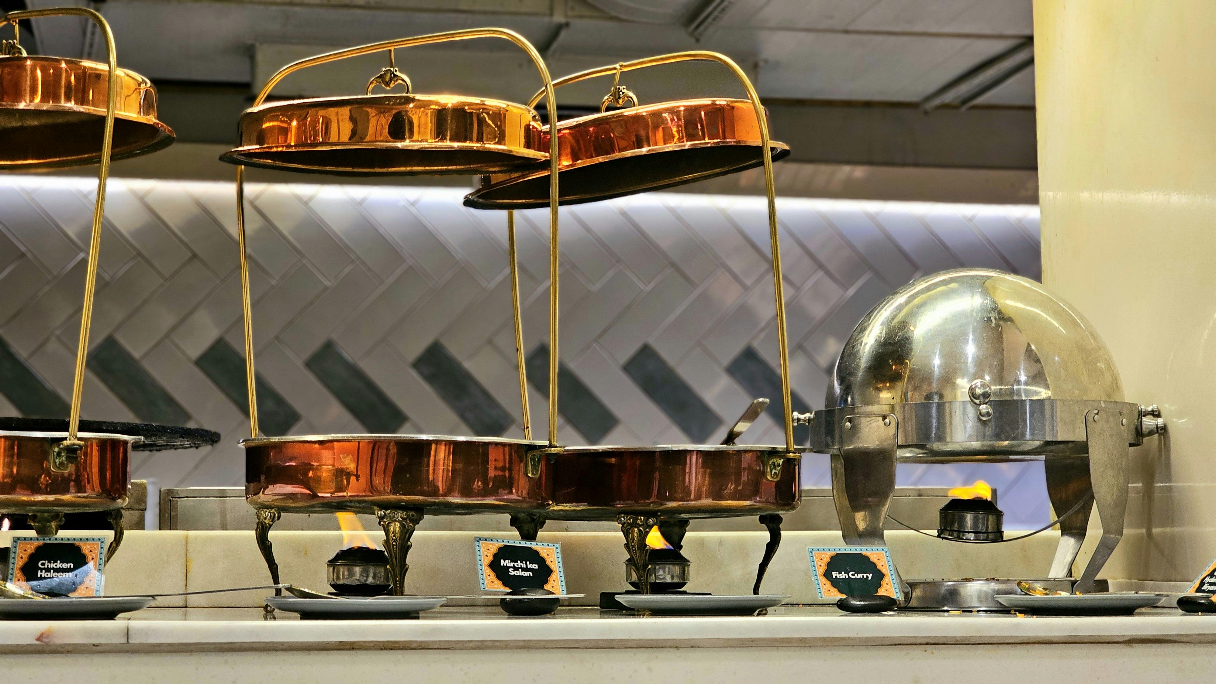 無料 ダイニングイベント用のレストランのセッティングにエレガントに配置された銅製のビュッフェウォーマー。 写真素材