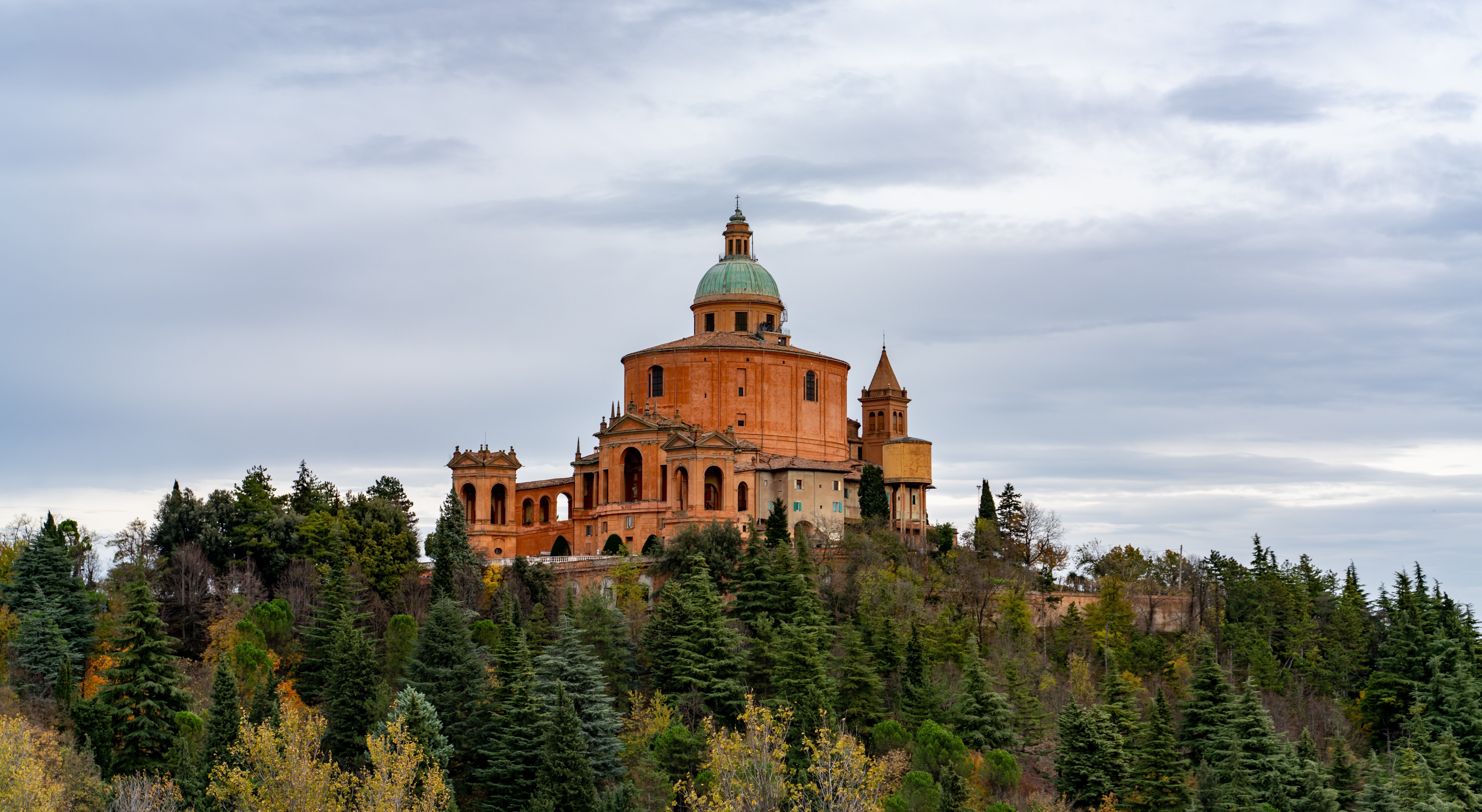 El histórico Santuario de la Madonna di San Luca en lo alto de una frondosa colina de Bolonia, Italia, bajo un cielo espectacular.
