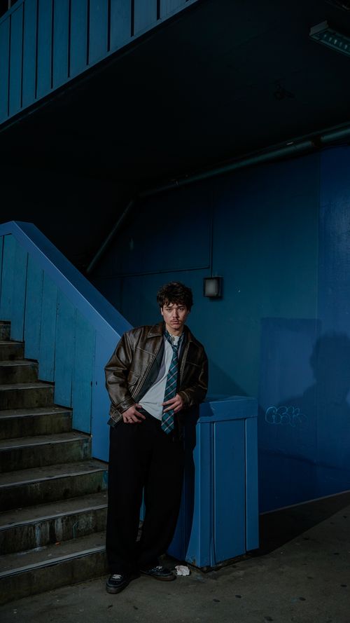 Free A stylish young man poses in an urban stairwell, creating a dramatic mood. Stock Photo