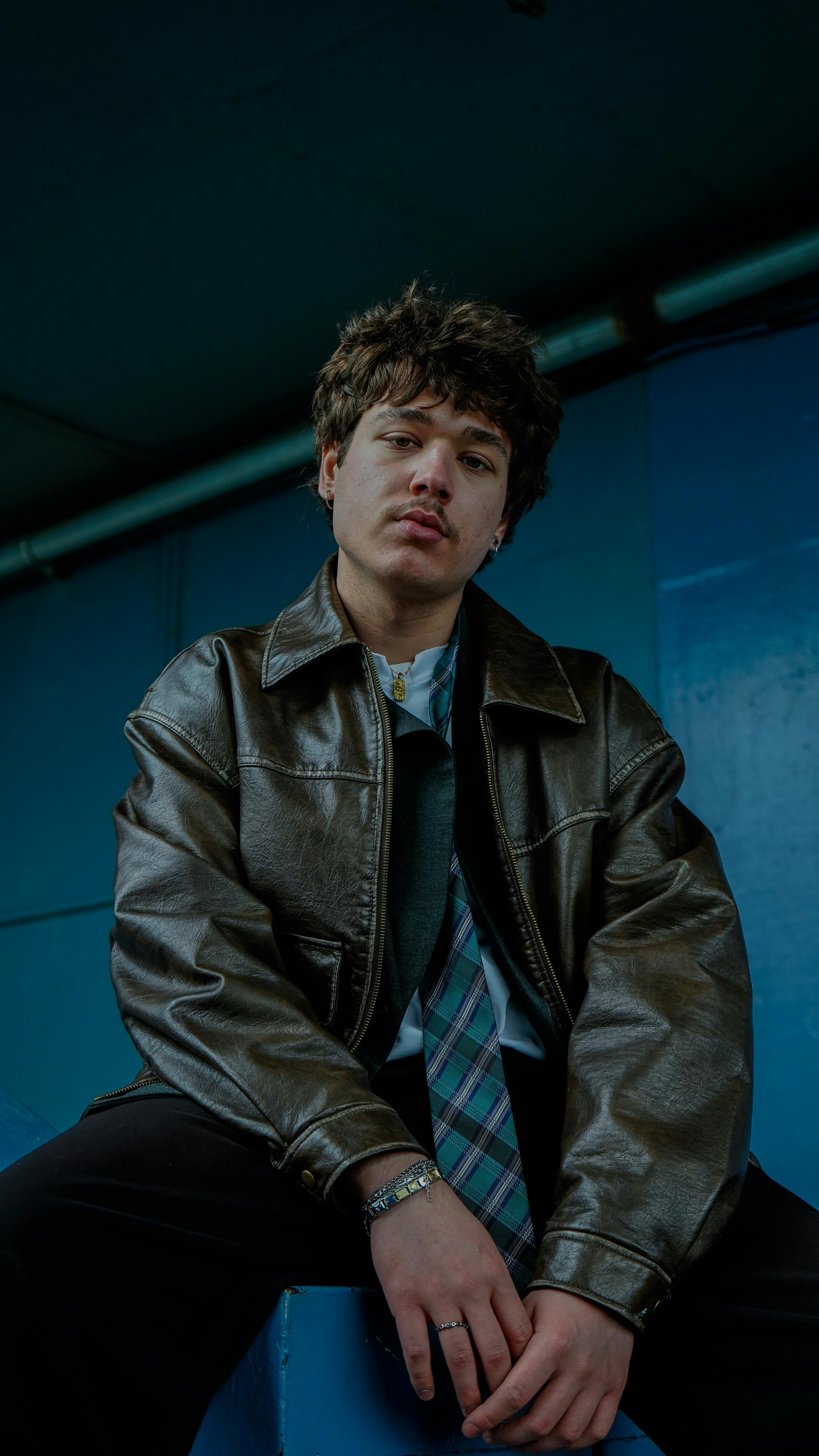 Free Portrait of a young man in a leather jacket indoors with a cool, moody vibe. Stock Photo