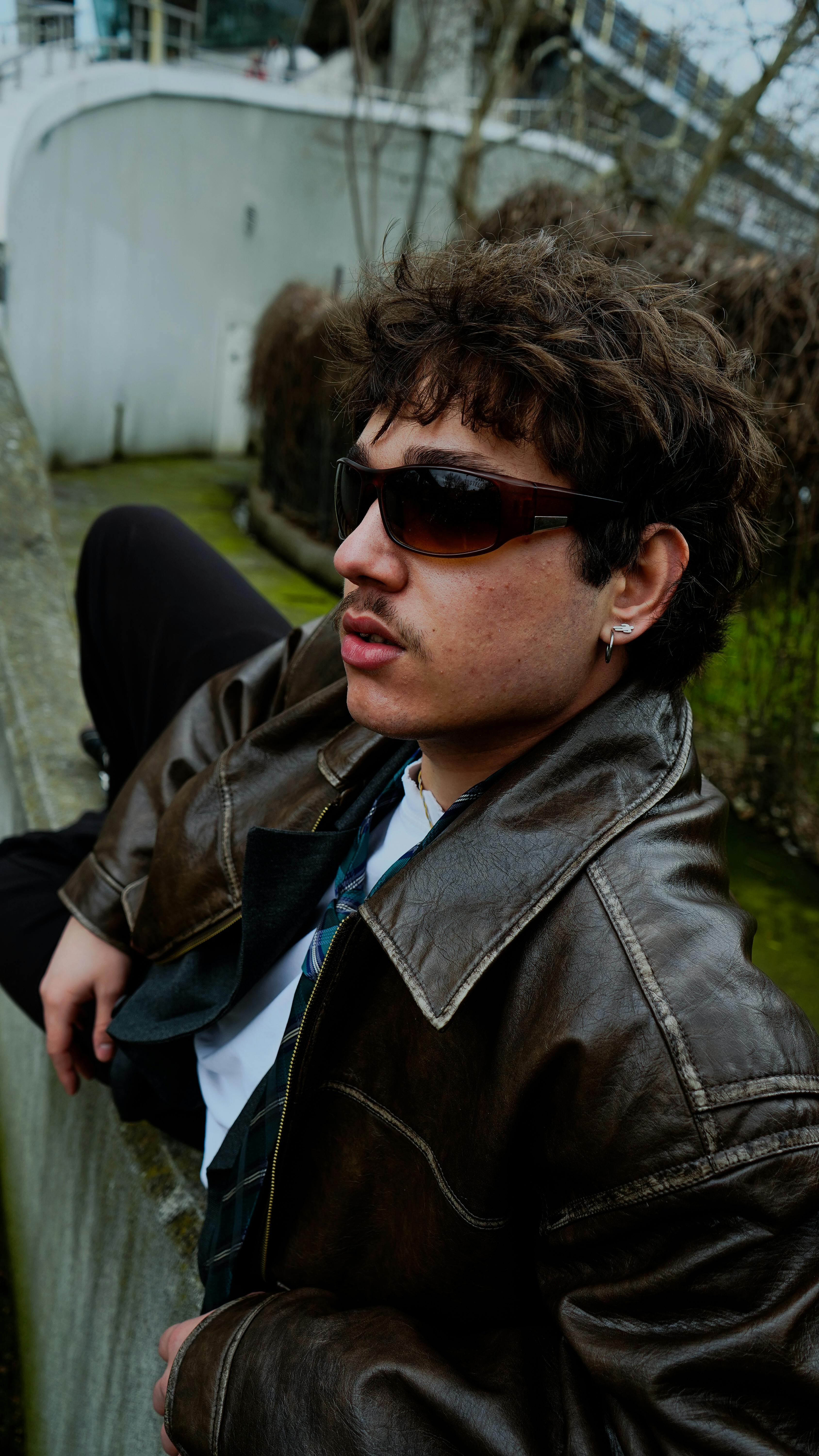 Free Young man with sunglasses and leather jacket outdoors, exuding retro style and attitude. Stock Photo
