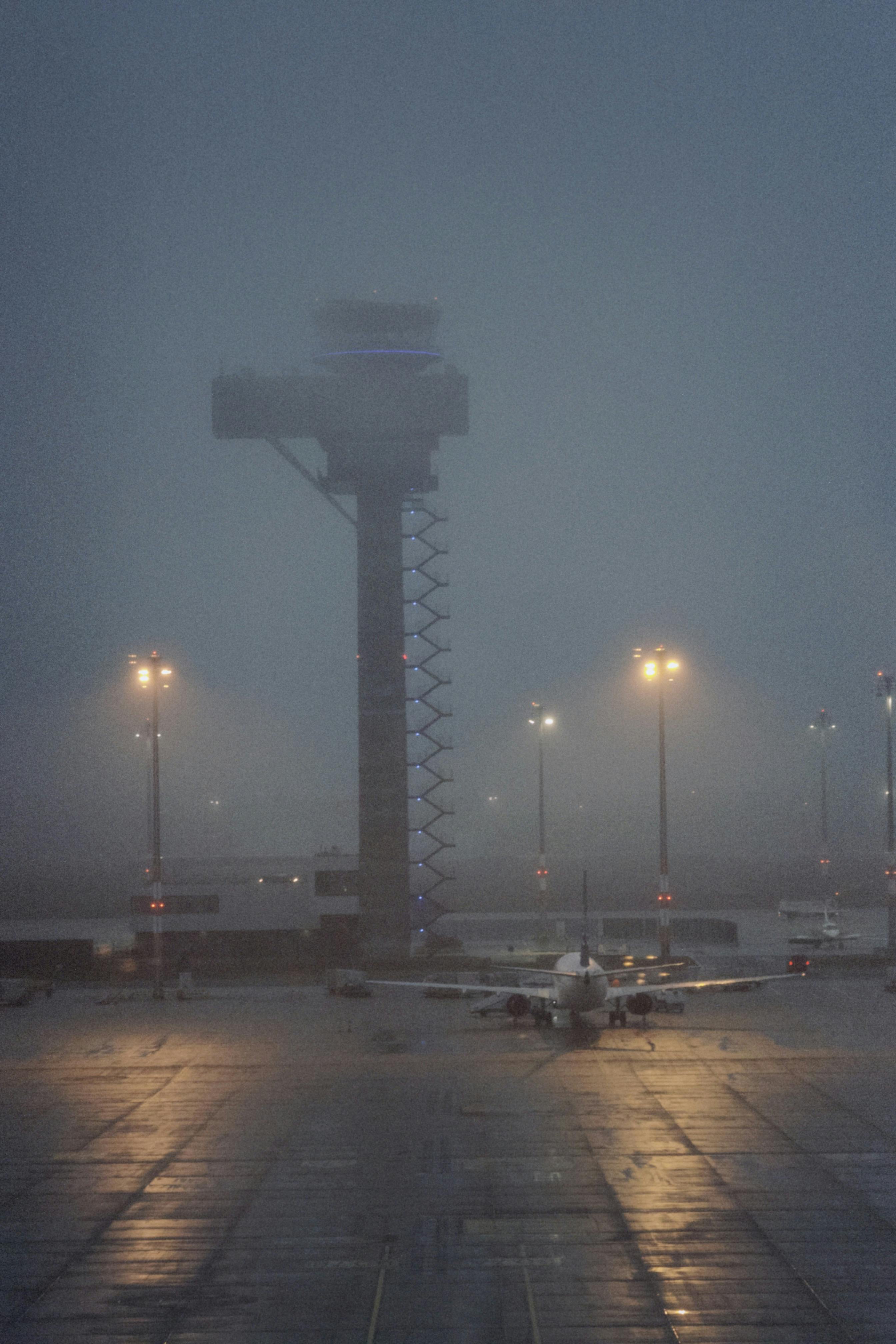無料 夕暮れ時に街灯に照らされた、管制塔と飛行機のある霧のかかった空港。 写真素材