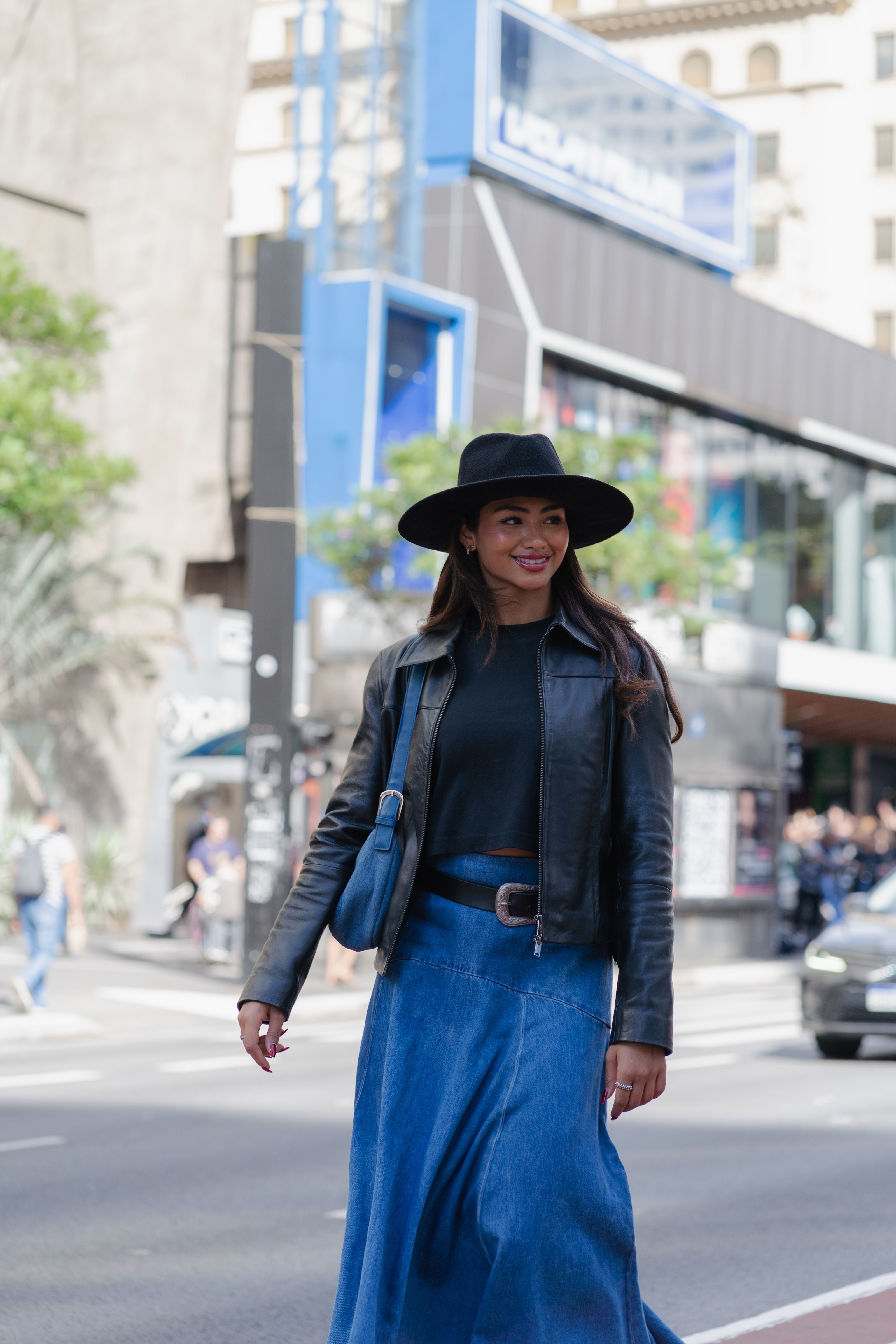 Mulher antenada na moda atravessando a rua com roupas elegantes, exalando confiança urbana e estilo moderno.