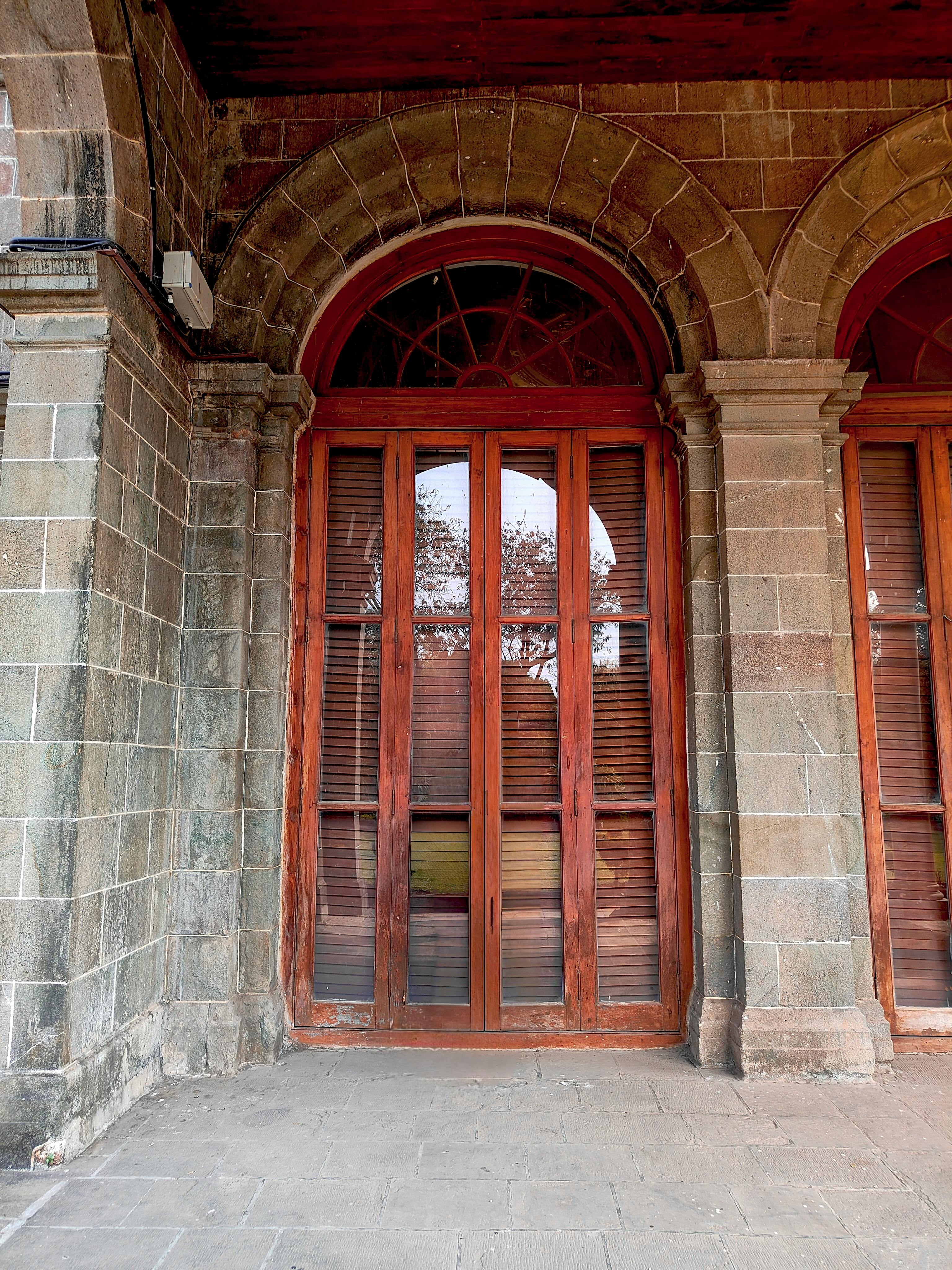 Gratis Pintu kayu melengkung yang elegan terpasang di bangunan batu bergaya pedesaan, memancarkan pesona klasik. Foto Stok