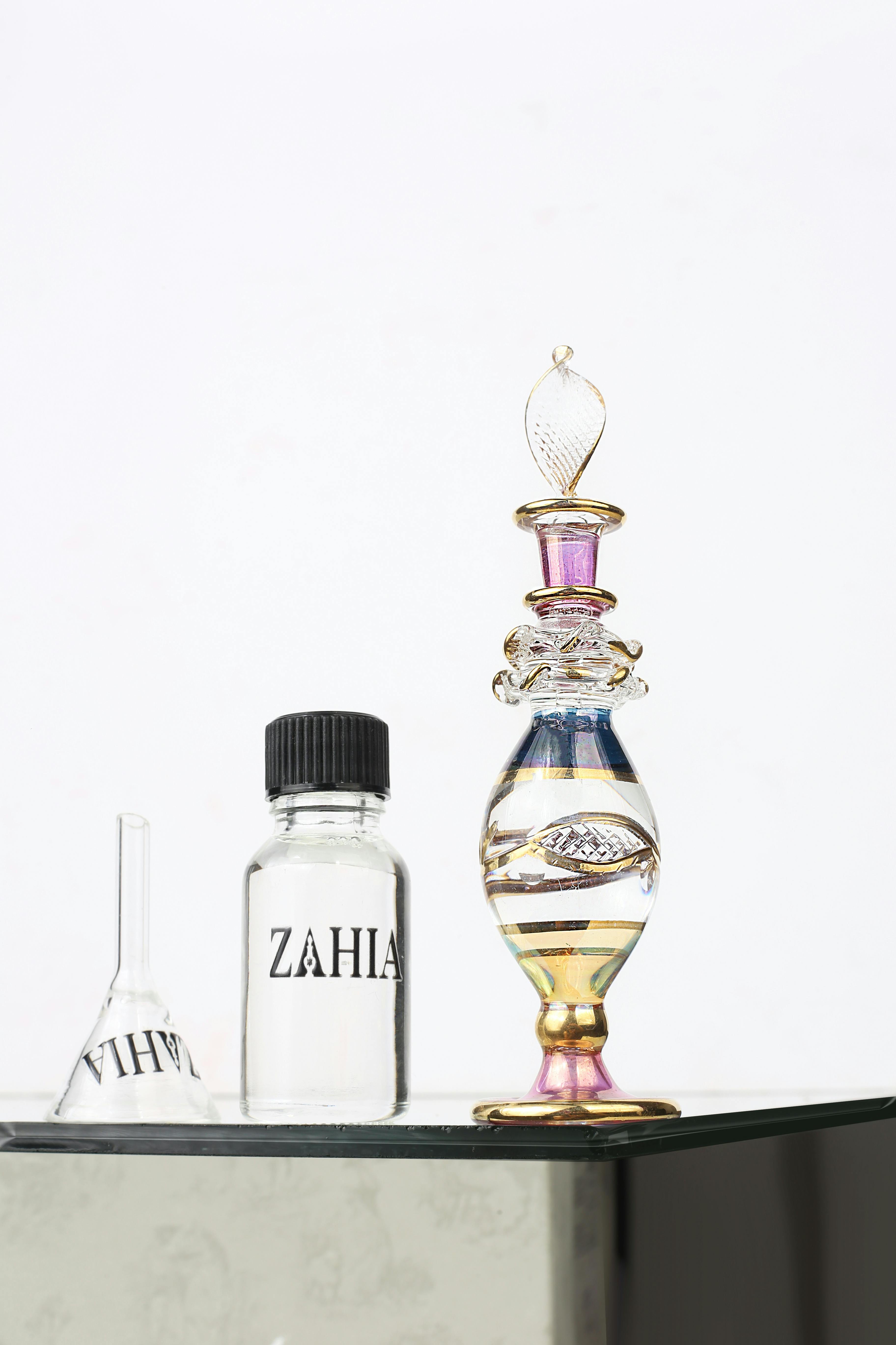 Free Beautiful glass perfume bottles elegantly arranged on a reflective surface against a white background. Stock Photo