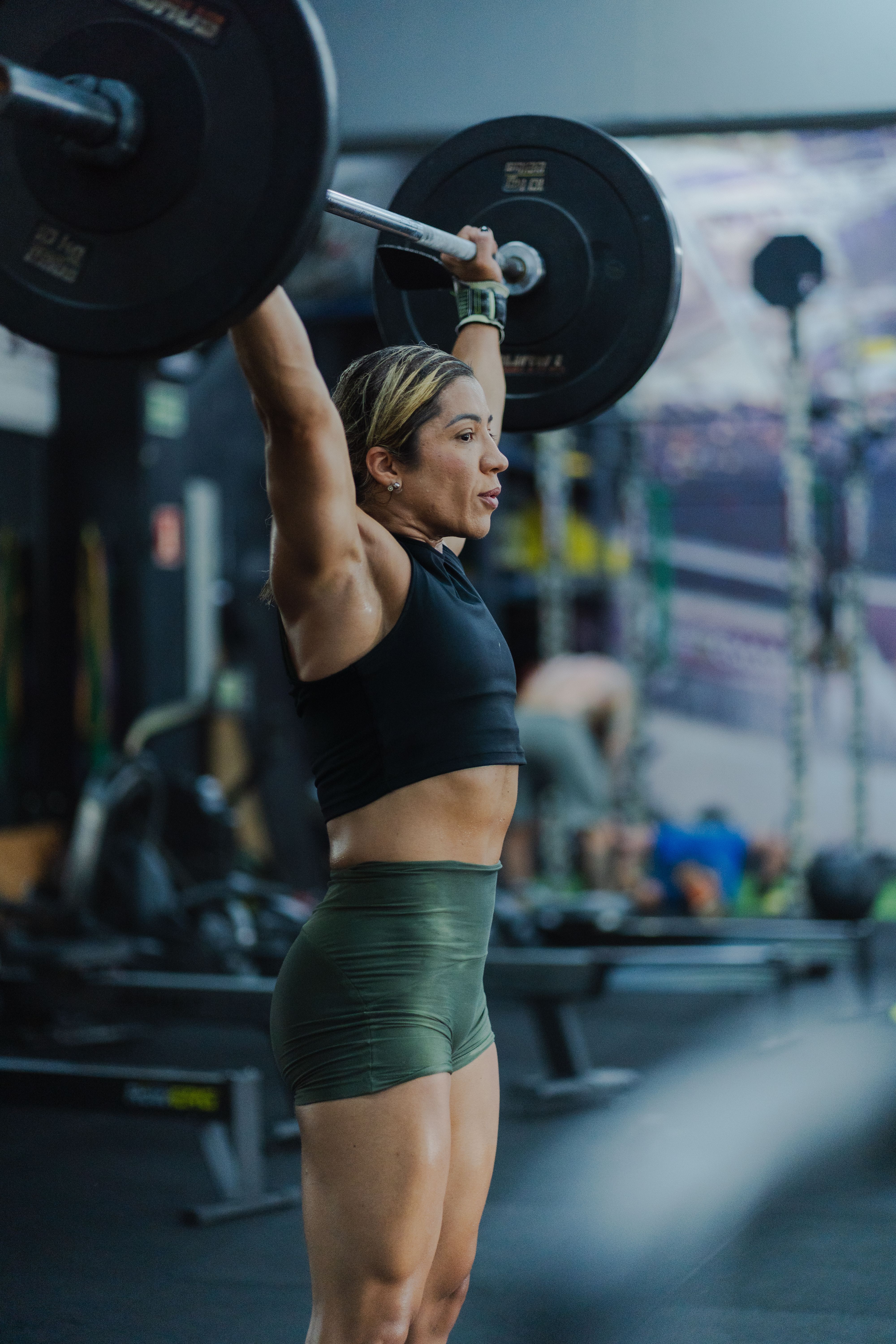 Determined woman performs weightlifting, a key component of hybrid athlete training, showcasing strength and fitness.