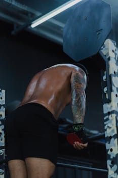 Back view of fit man with tattoos working out in the gym.
