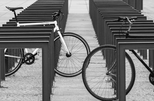 Monochrome image showing two bicycles parked at modern parking station.
