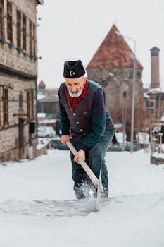 An elderly man shoveling snow in the historic district of Erzurum, Türkiye, during winter.