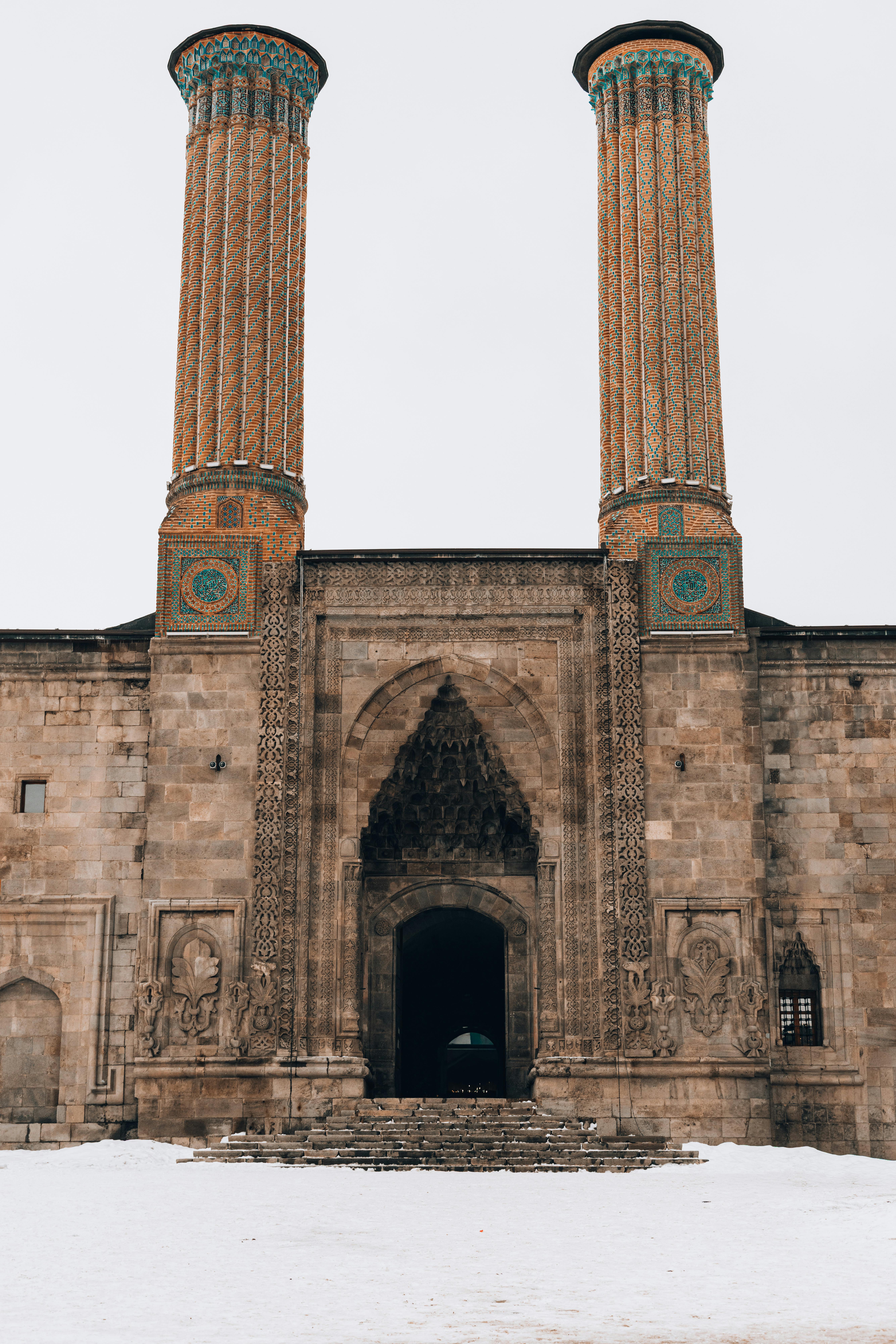 無料 トルコのエルズルムにあるツイン・ミナレット・マドラサの魅惑的な眺め。雪がその歴史的建築を際立たせています。 写真素材