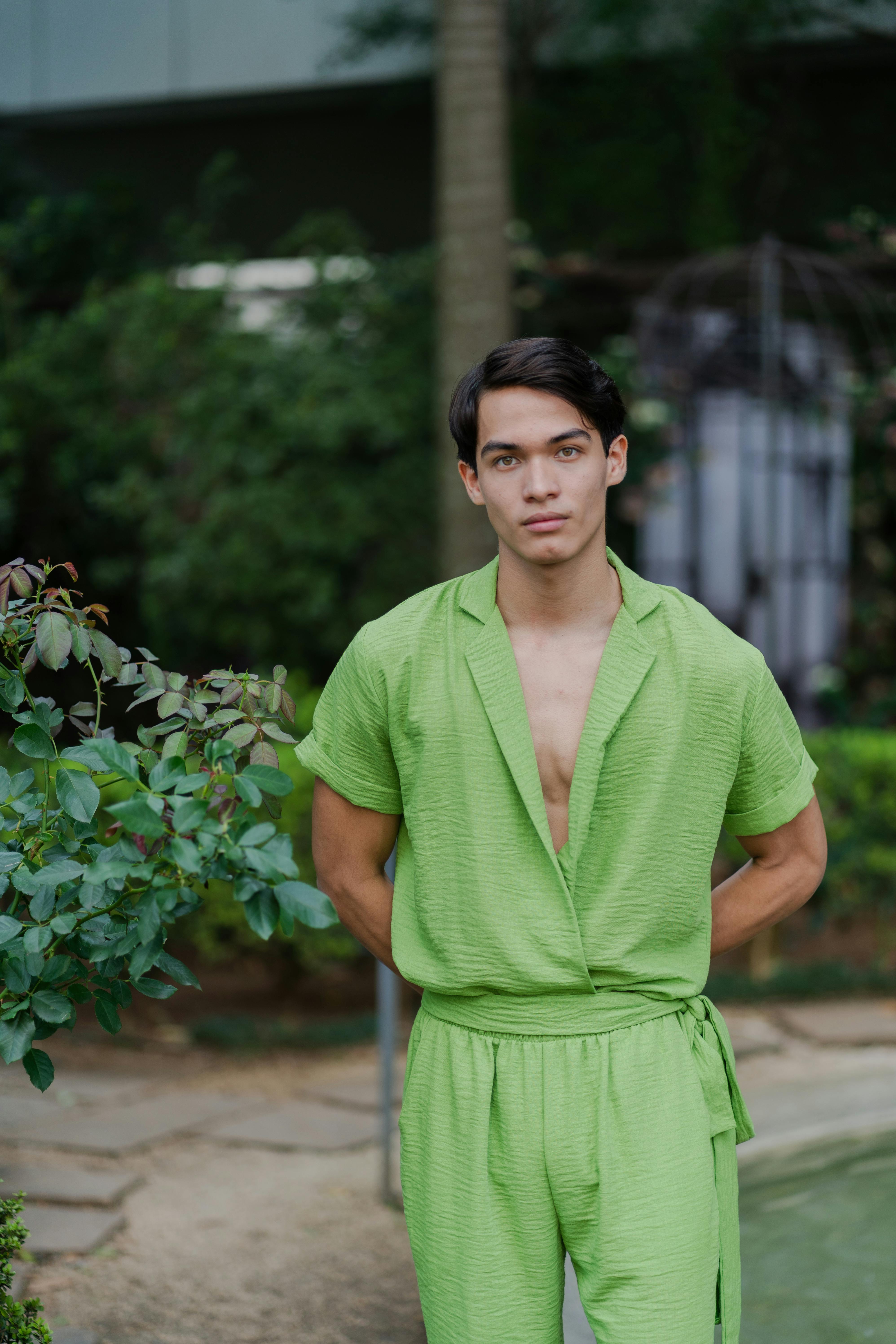 Free Portrait of a young man wearing a green outfit standing in a garden. Stock Photo