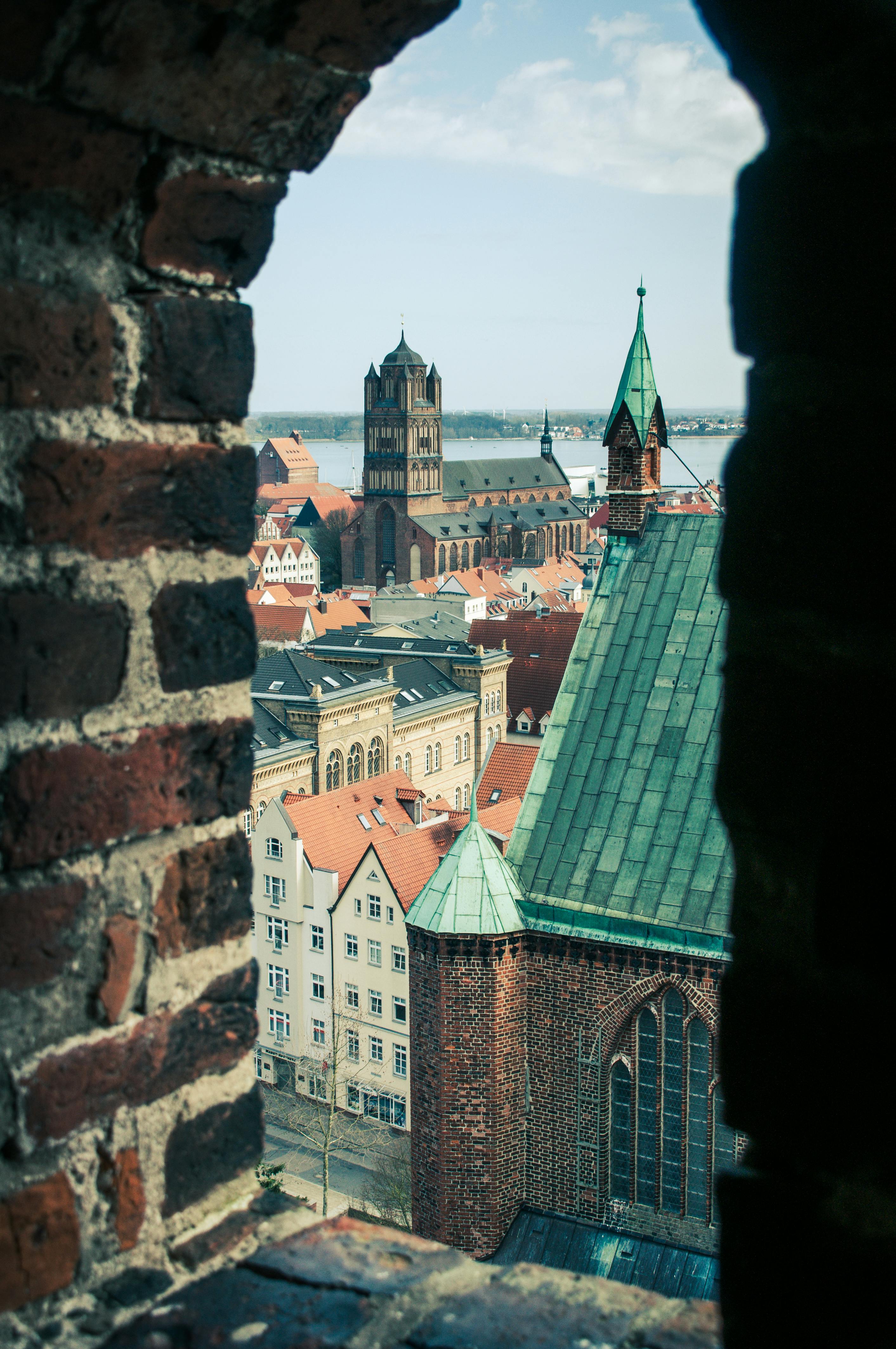 無料 ドイツのシュトラールズントにある歴史的建造物と教会の尖塔の魅惑的な景色。 写真素材