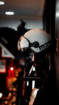 A white helmet hangs on a wall, illuminated by red lights in a dimly lit room.