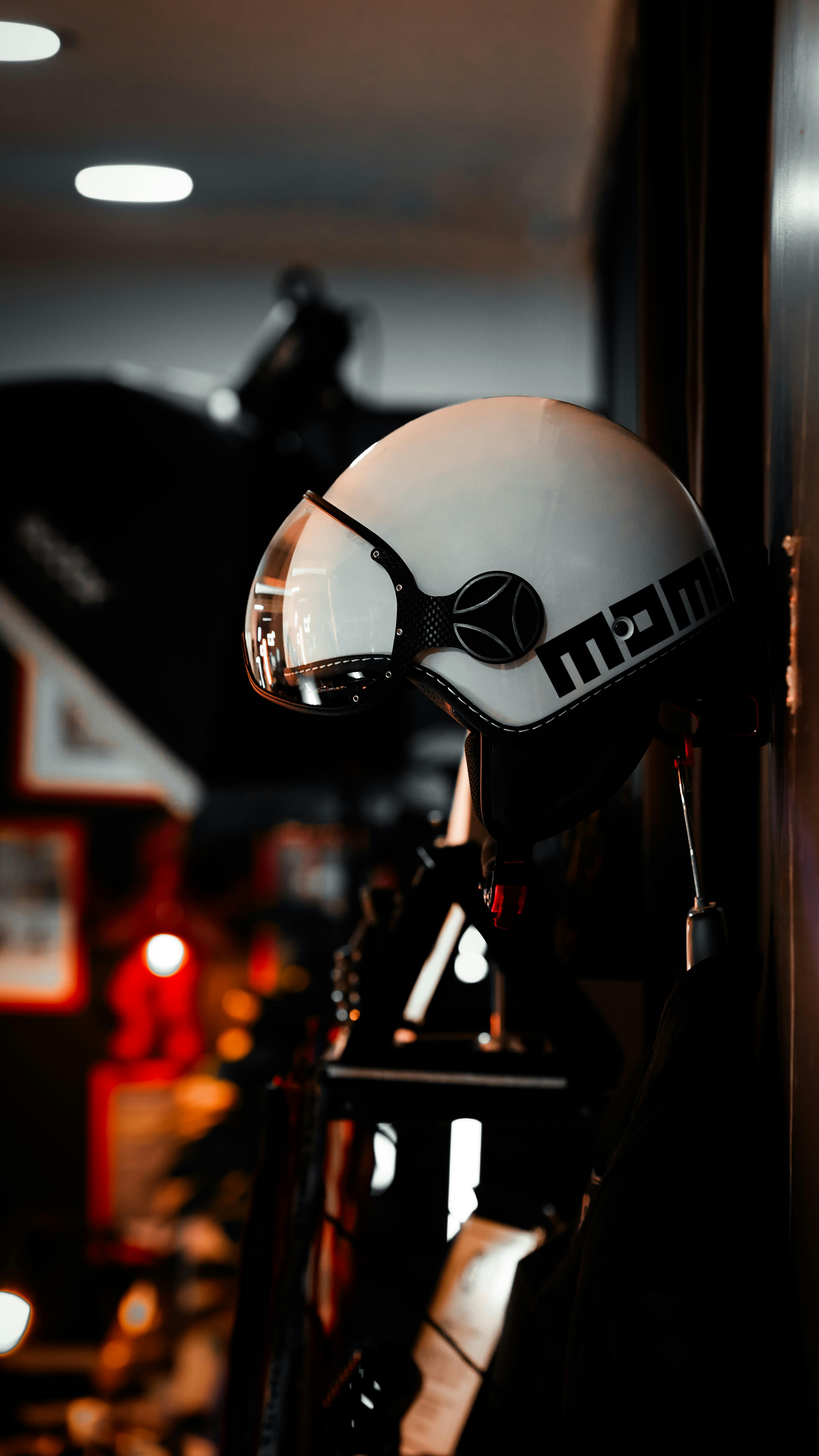Free A white helmet hangs on a wall, illuminated by red lights in a dimly lit room. Stock Photo