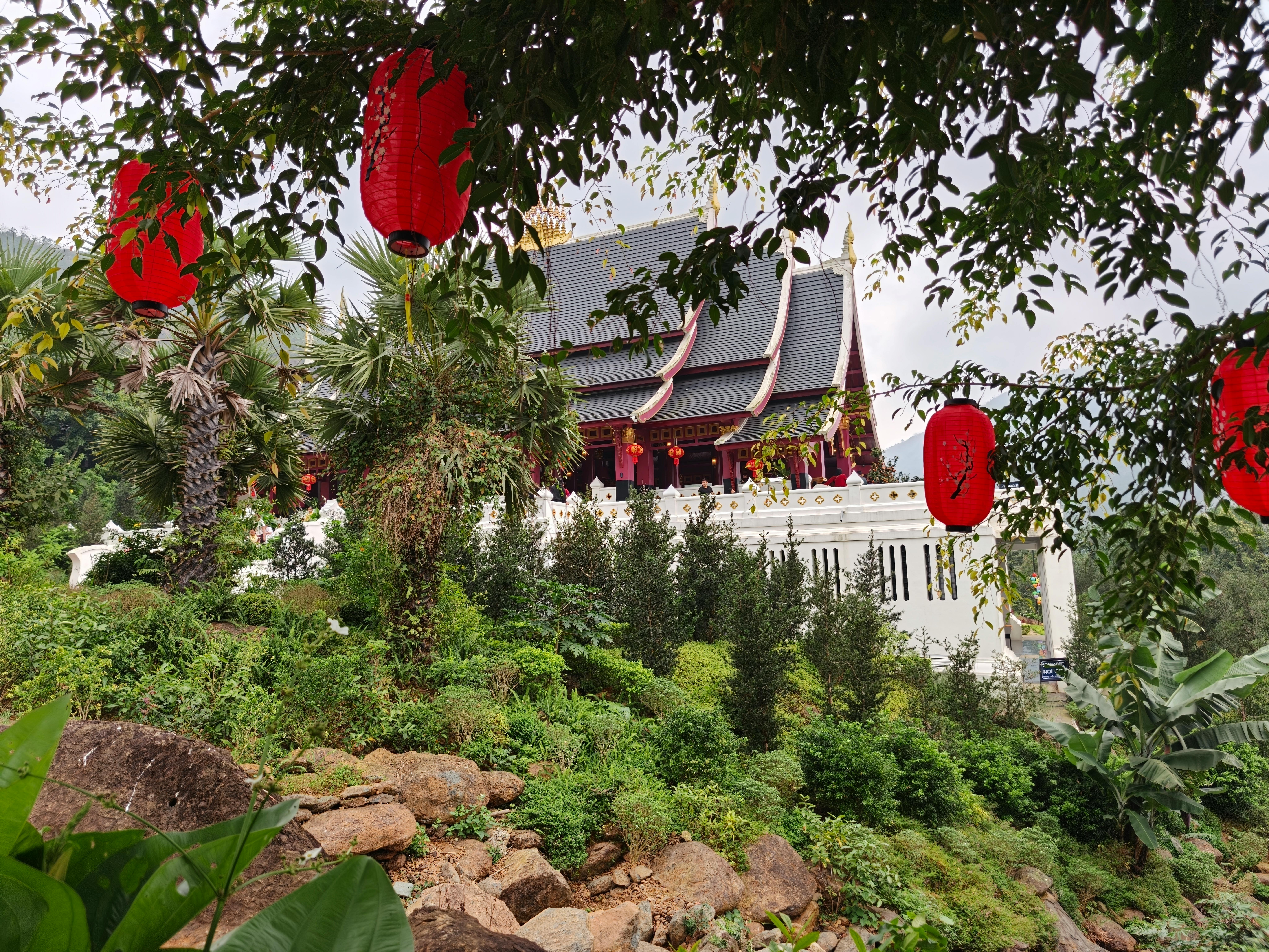 無料 豊かな緑と祭りの赤い提灯に囲まれた静かなアジアの寺院。 写真素材