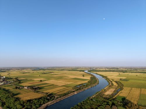 Free Breathtaking aerial view of Indian farmland with meandering river and canal under clear blue sky. Stock Photo