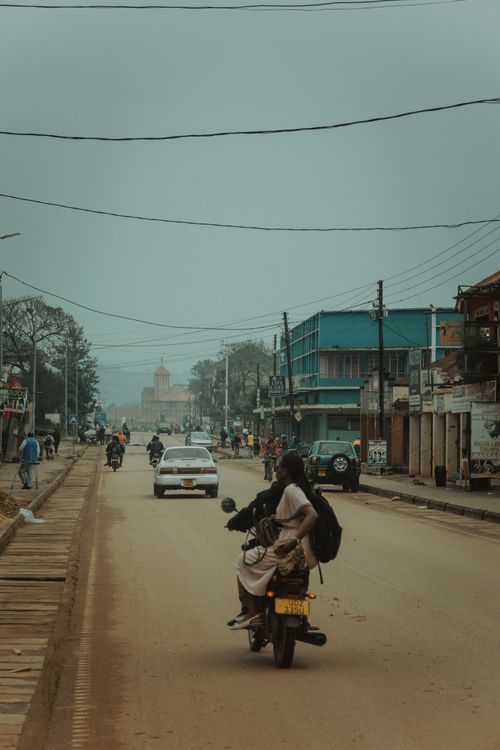 Free Street scene with motorcycles and cars on a dusty road, showcasing everyday life. Stock Photo