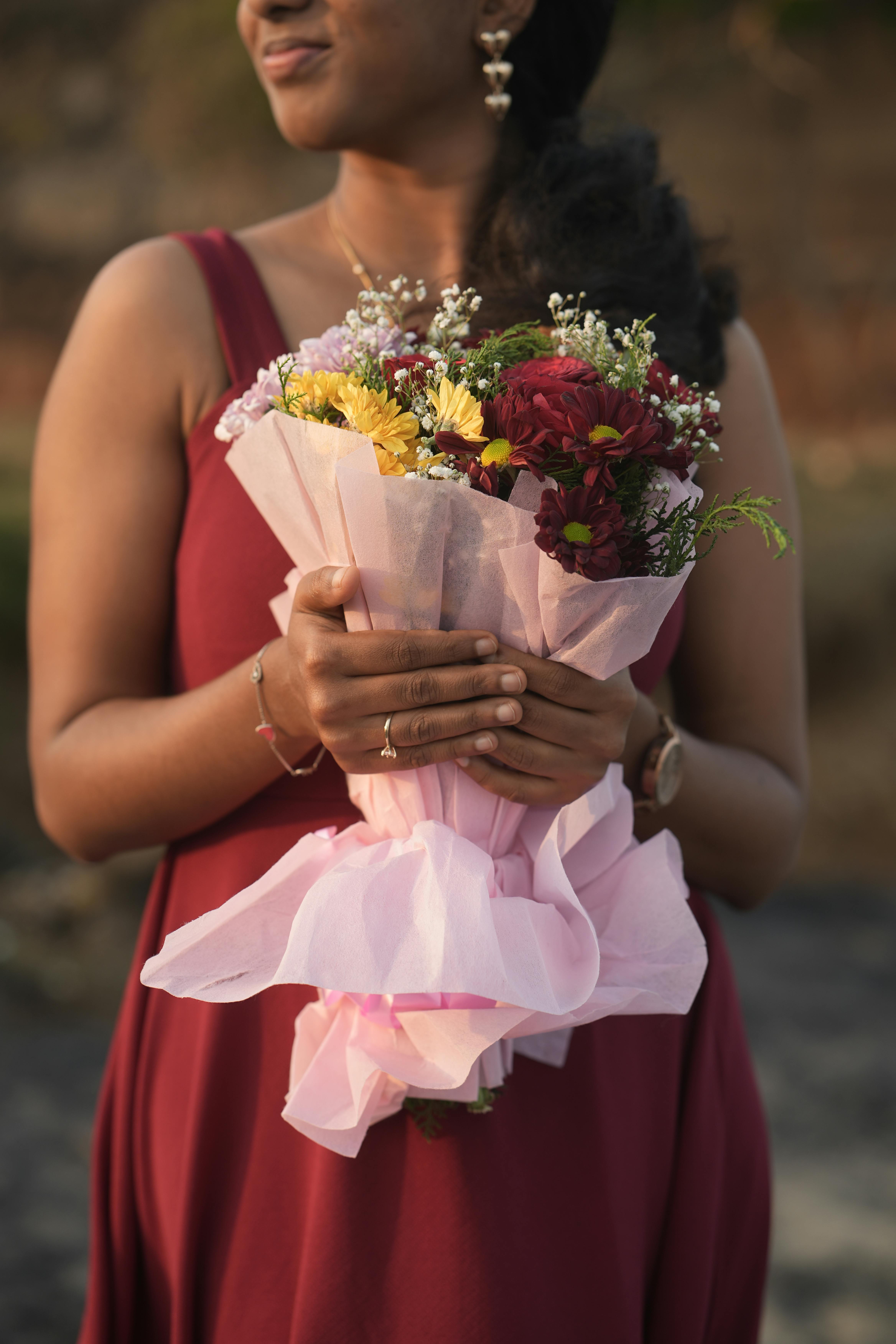 [ColoSach]-close-up-of-a-woman-in-a-red-dress-holding-a-colorful-floral-bouquet-outdoors.