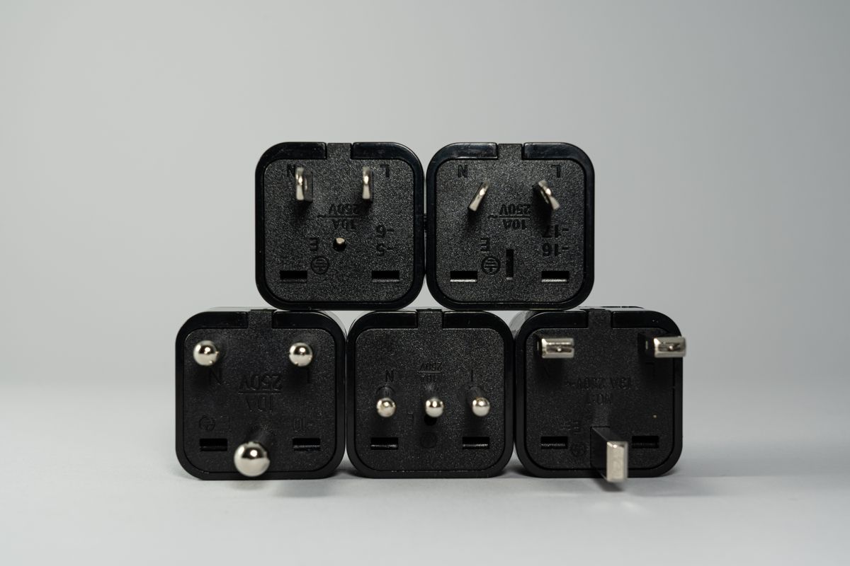 A row of black wall outlets and plugs, the kind of household circuit a space heater smart plug connects to