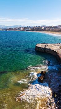 Aerial view of the scenic coastline in Santander, Spain with vibrant blue waters and distant mountains.