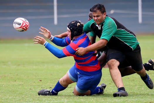 Rugby players in an intense tackle during a match on a grassy field. Action-packed sports moment.