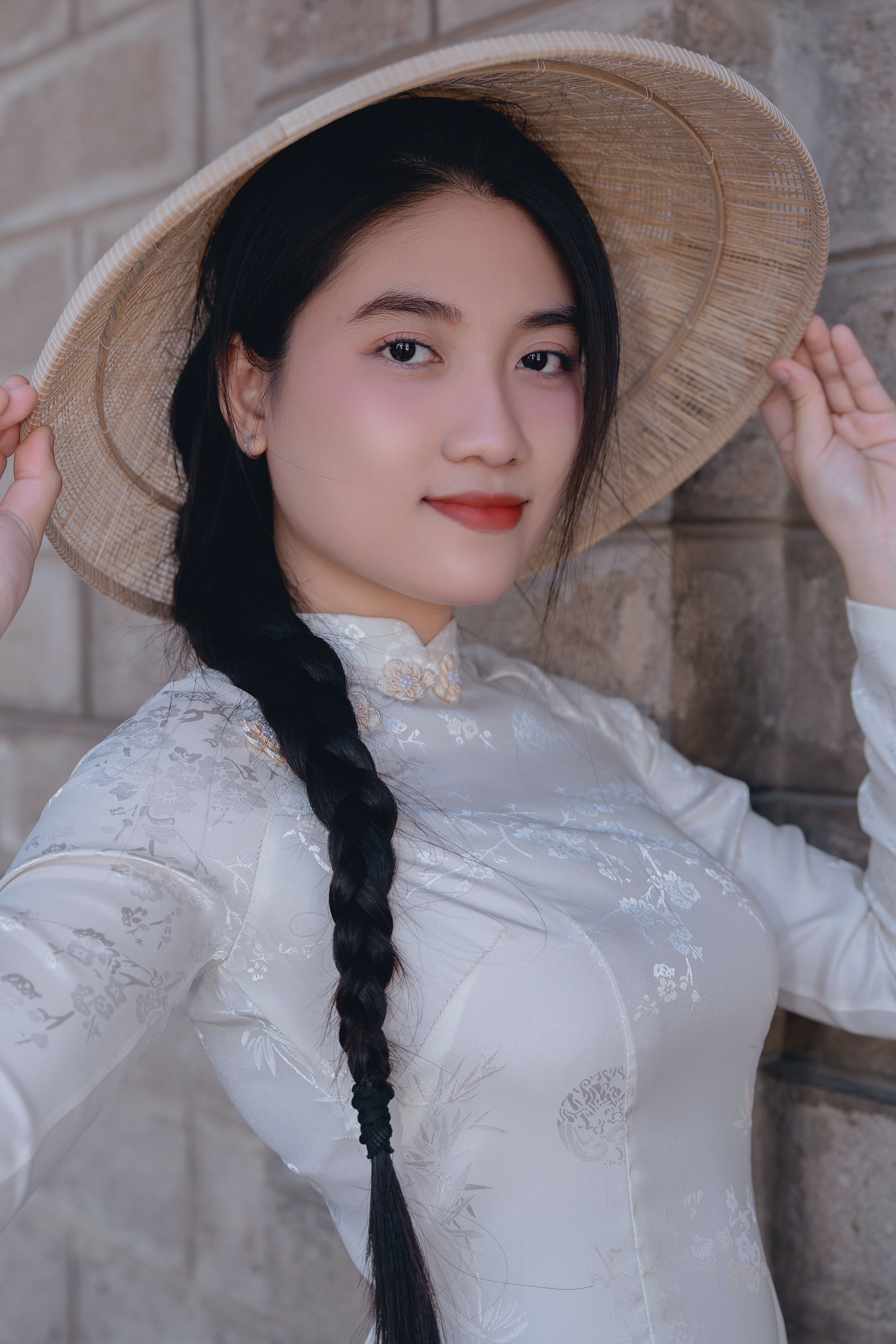 Close-up portrait of an adult woman in traditional Vietnamese dress with a bamboo hat.