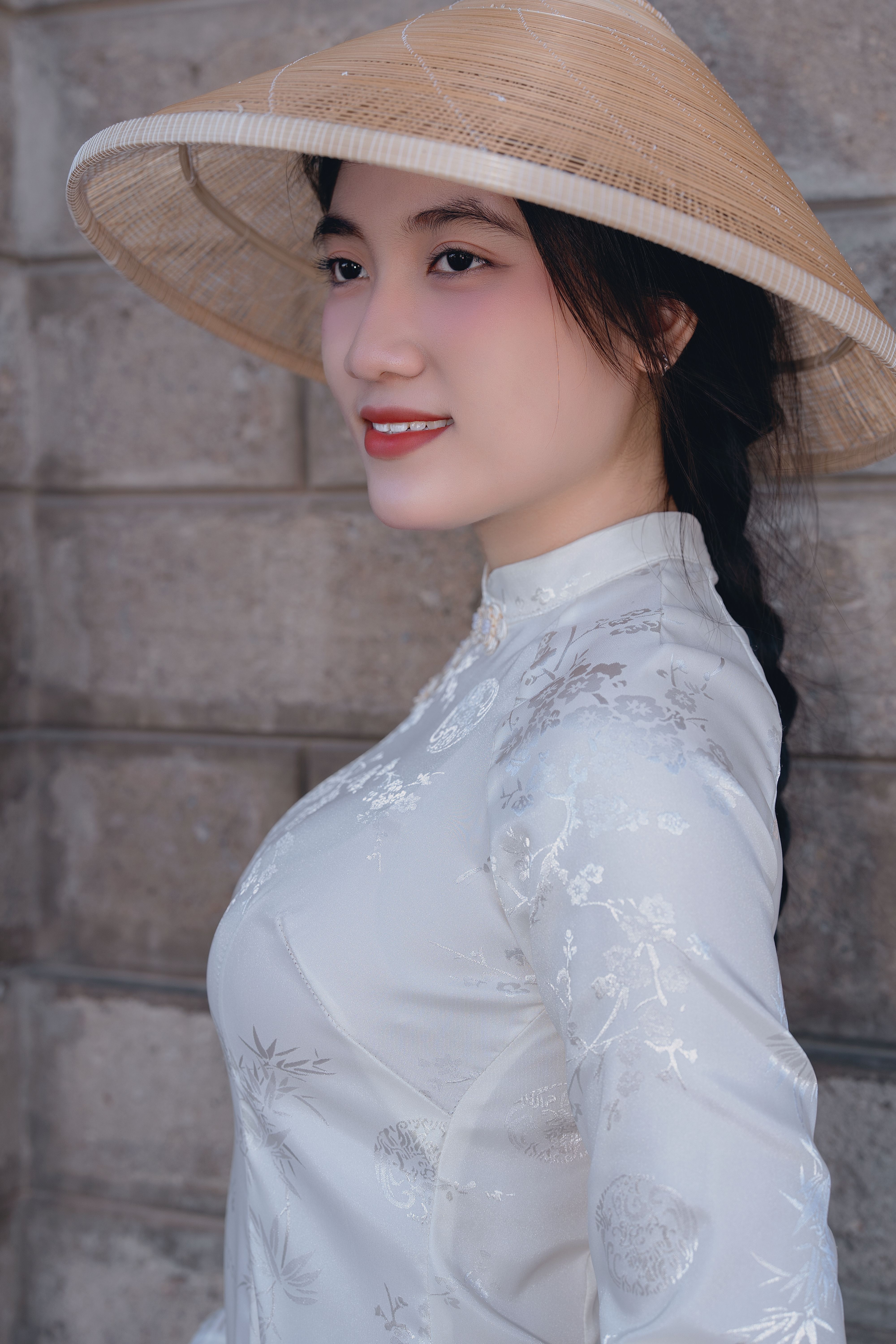 Portrait of a woman in a white ao dai and conical hat, showcasing Vietnamese culture.