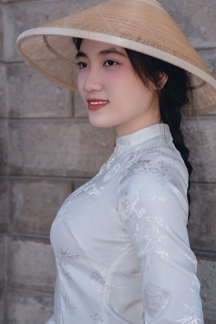 Portrait of a woman in a white ao dai and conical hat, showcasing Vietnamese culture.