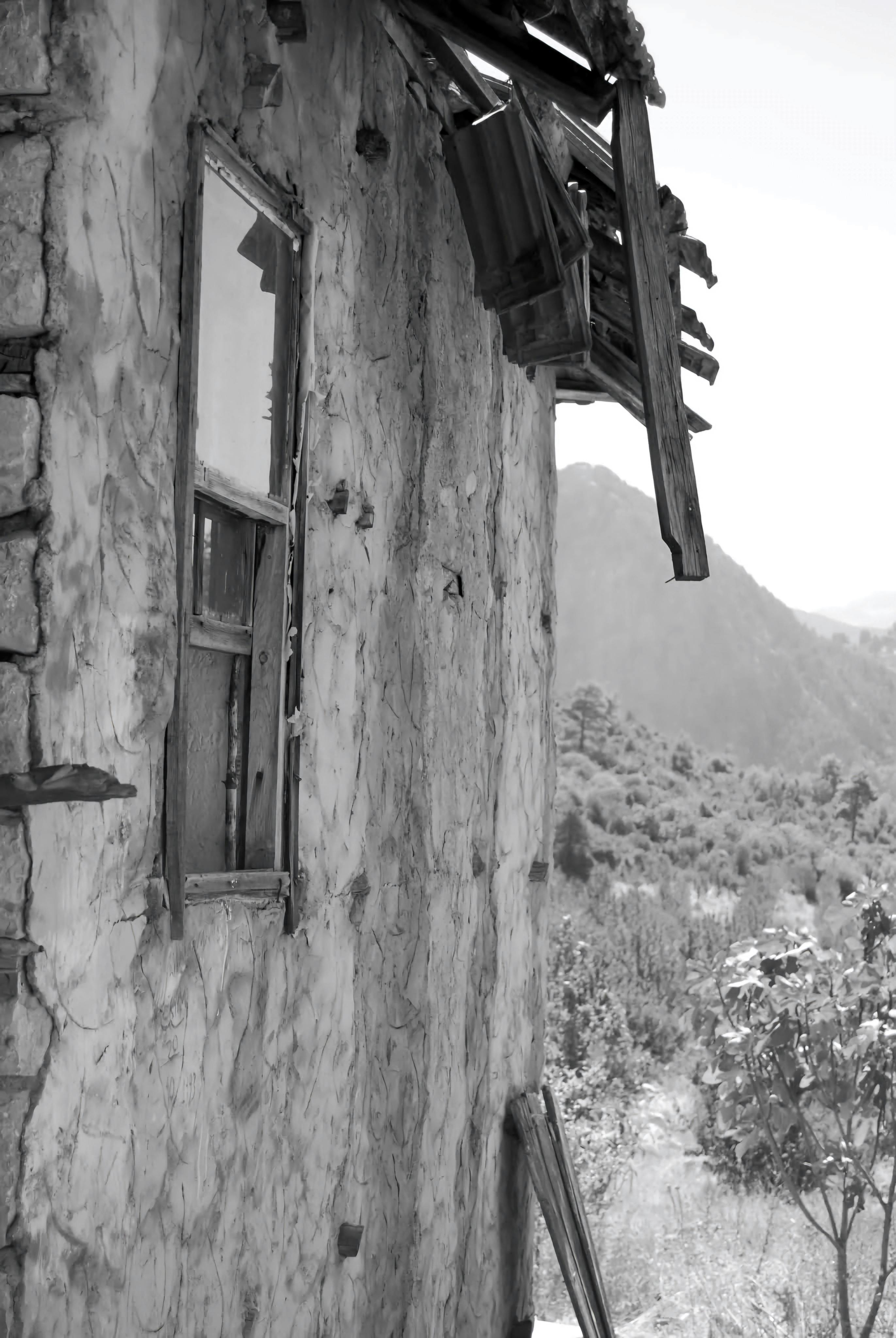 Gratuit Image en noir et blanc d'un bâtiment rustique et délabré offrant une vue pittoresque sur les montagnes. Photos