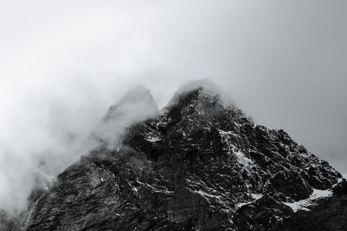 Free Black and white image of imposing snow-covered mountain peaks shrouded in mist. Stock Photo