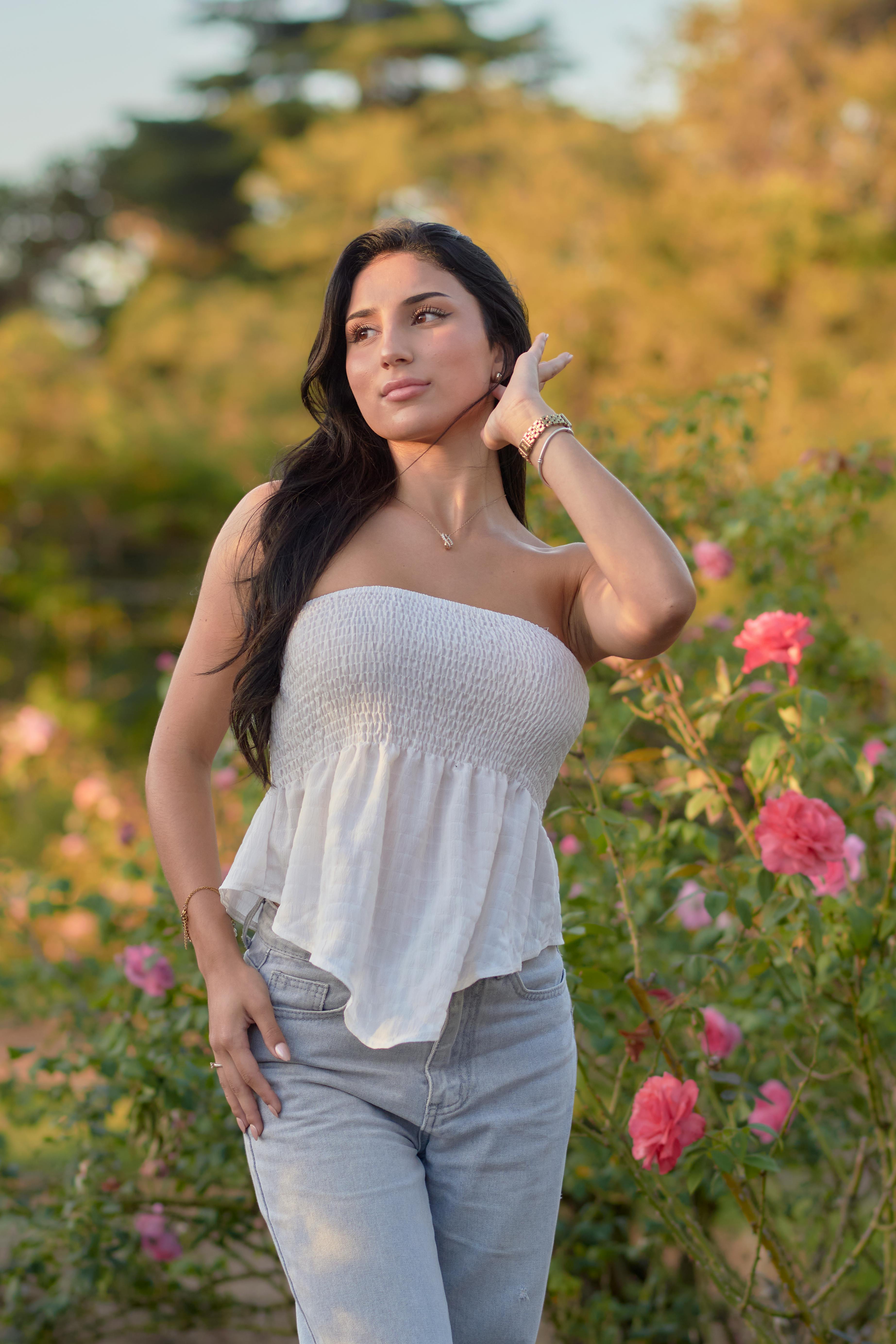 Free Elegant young woman posing in a rose garden with soft summer lighting. Stock Photo