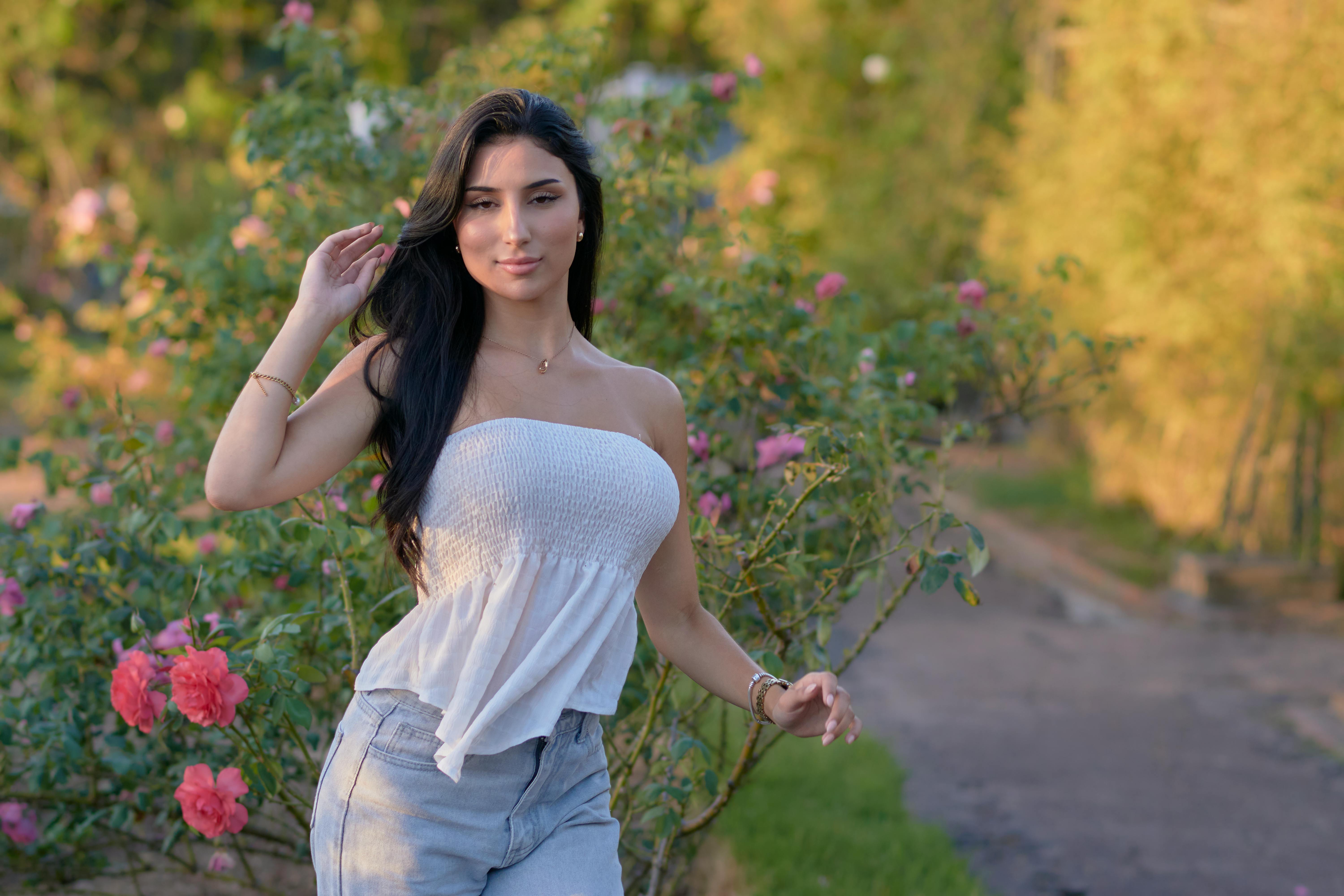 бесплатная Молодая женщина наслаждается теплым днем ​​в парке Монтевидео, в окружении цветущих роз. Стоковое фото