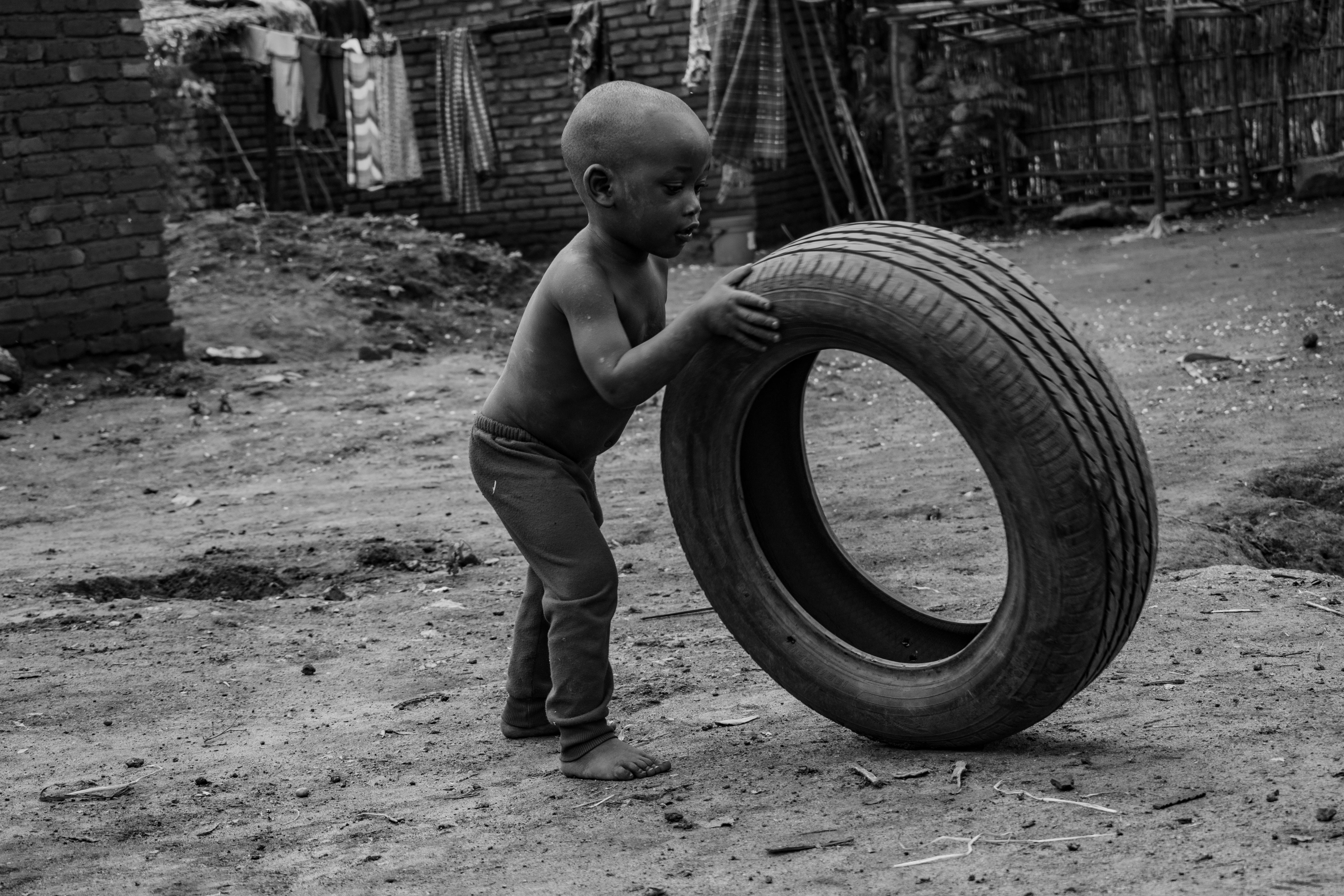 無料 マラウイのドワでタイヤで遊ぶ幼い子供の白黒写真。 写真素材