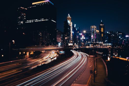 Long exposure shot of city traffic at night showcasing dynamic light trails and illuminated skyscrapers.