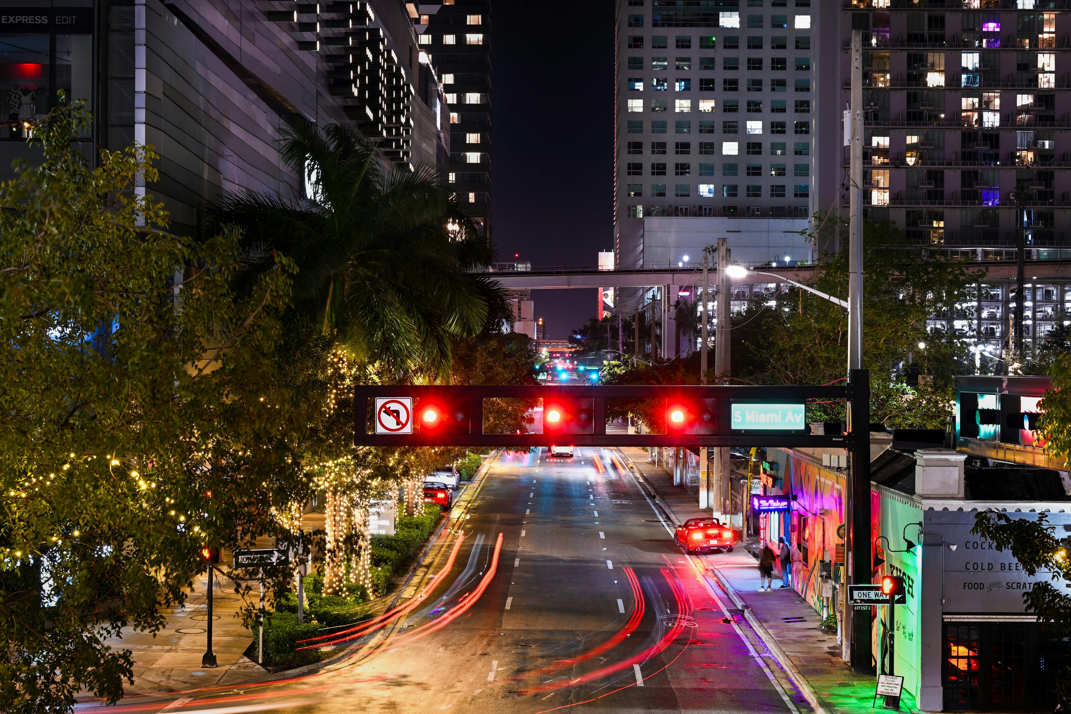 無料 光の軌跡とライトアップされた建物が特徴的なサウス マイアミ アベニューの活気ある夜景。 写真素材