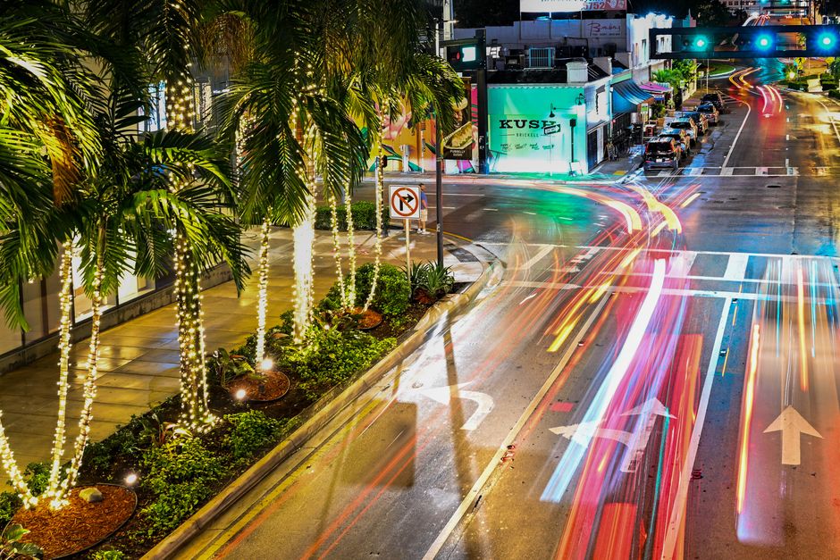 Dynamic night scene of a colorful Miami street with vibrant light trails and palm trees.