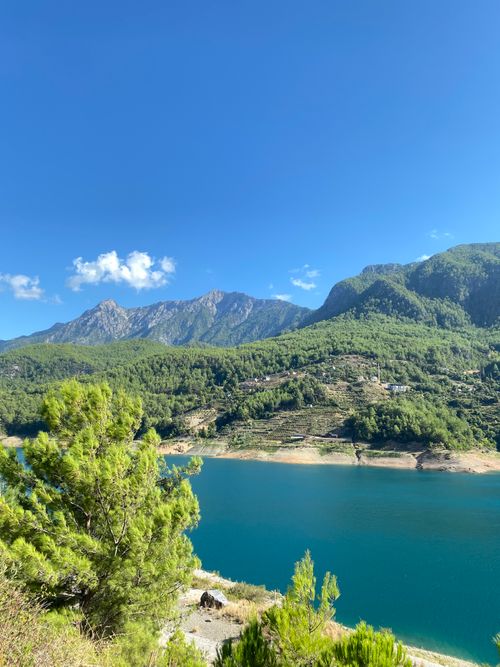 Free Beautiful landscape with green mountains and a clear blue lake under a bright sky. Stock Photo